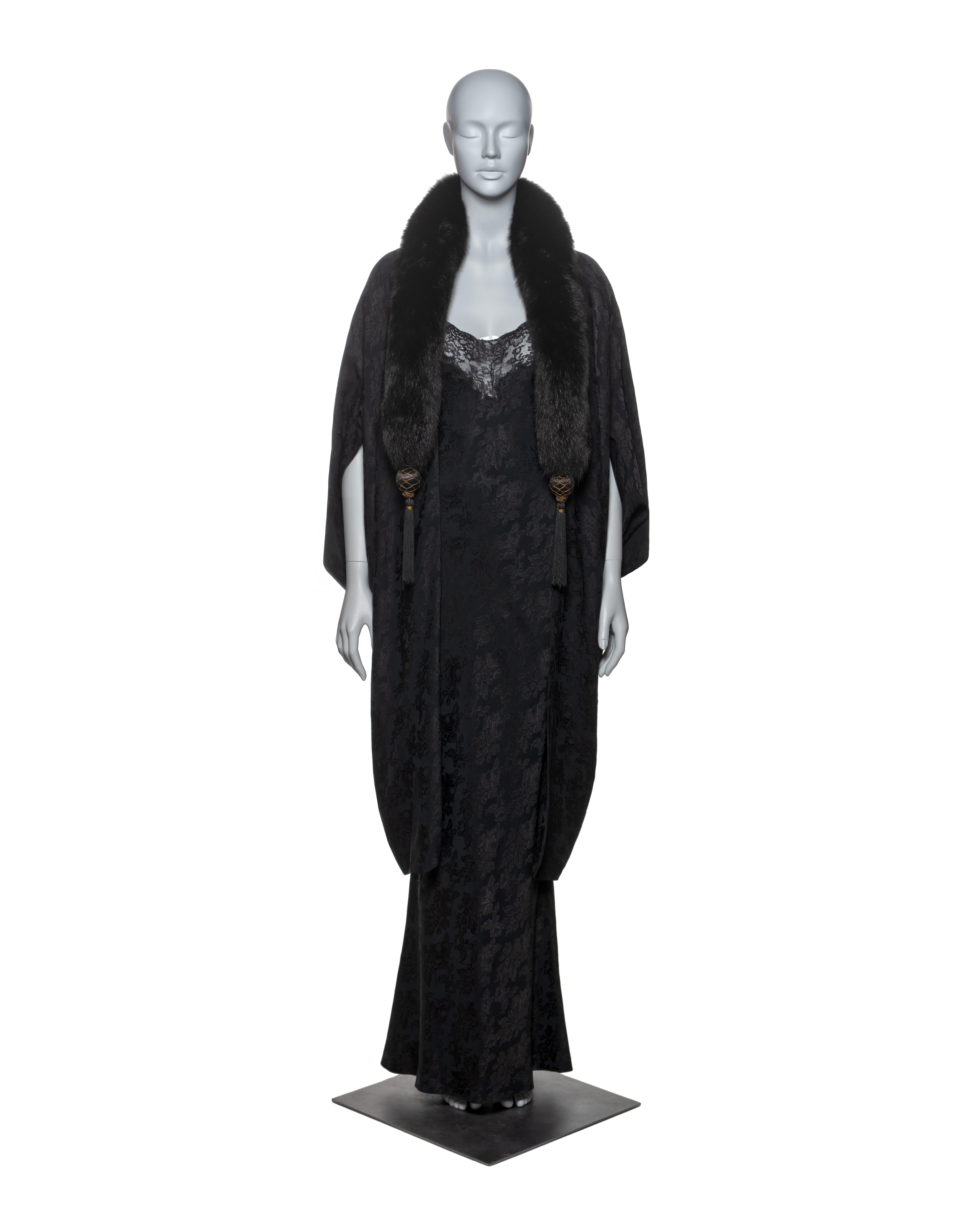 This Christian Dior by John Galliano ensemble consists of a jacquard coat and matching dress, both made from an acetate and viscose blend fabric featuring a subtle floral jacquard pattern. The coat is lined with silk and has a luxurious fox fur