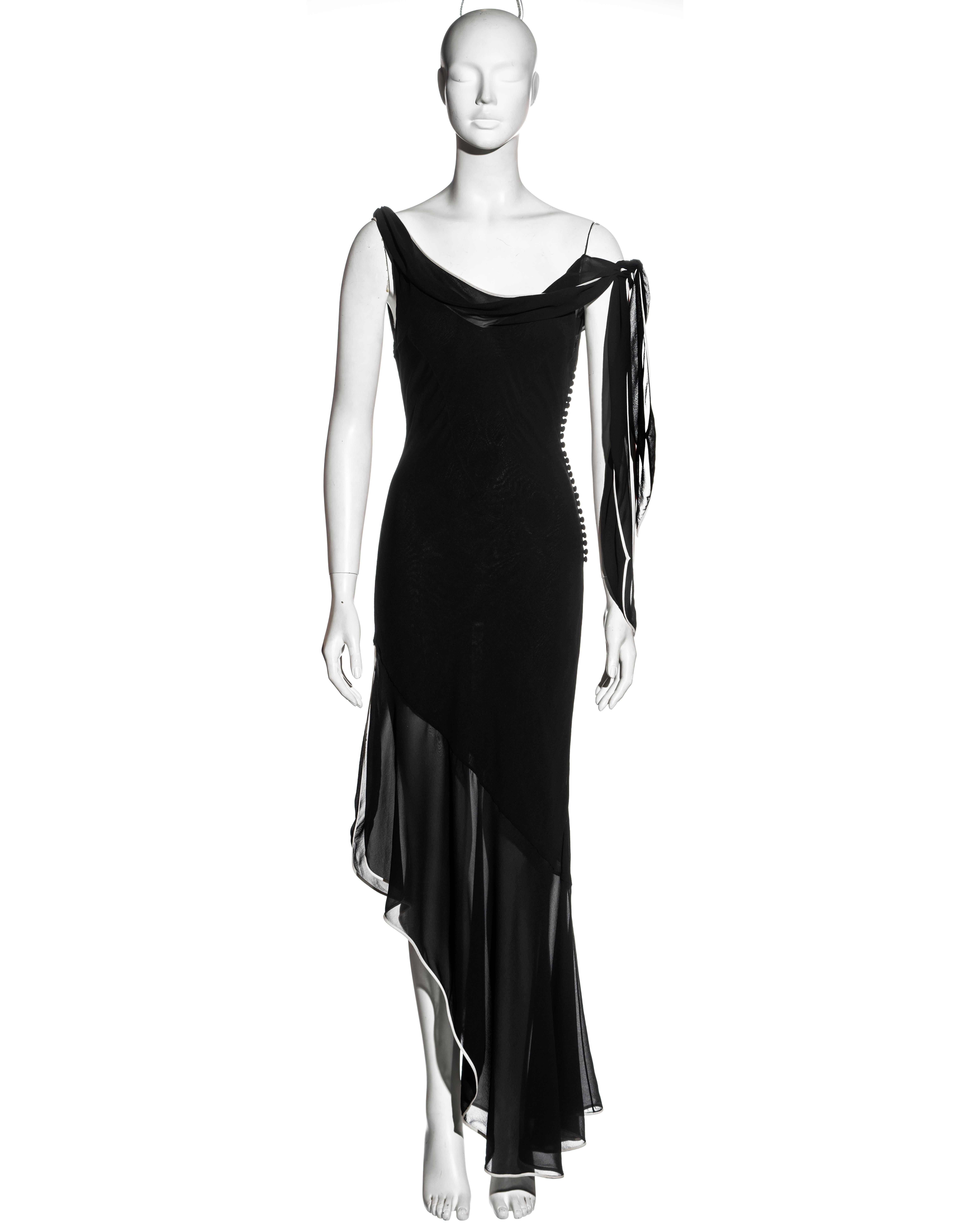 ▪ Christian Dior black silk evening dress
▪ Designed by John Galliano
▪ Cowl neckline with long ties to the shoulder
▪ Spaghetti straps
▪ Bias-cut
▪ White trim
▪ Asymmetric hemline with thigh-high leg slit
▪ Fabric buttons at the side opening
▪ FR