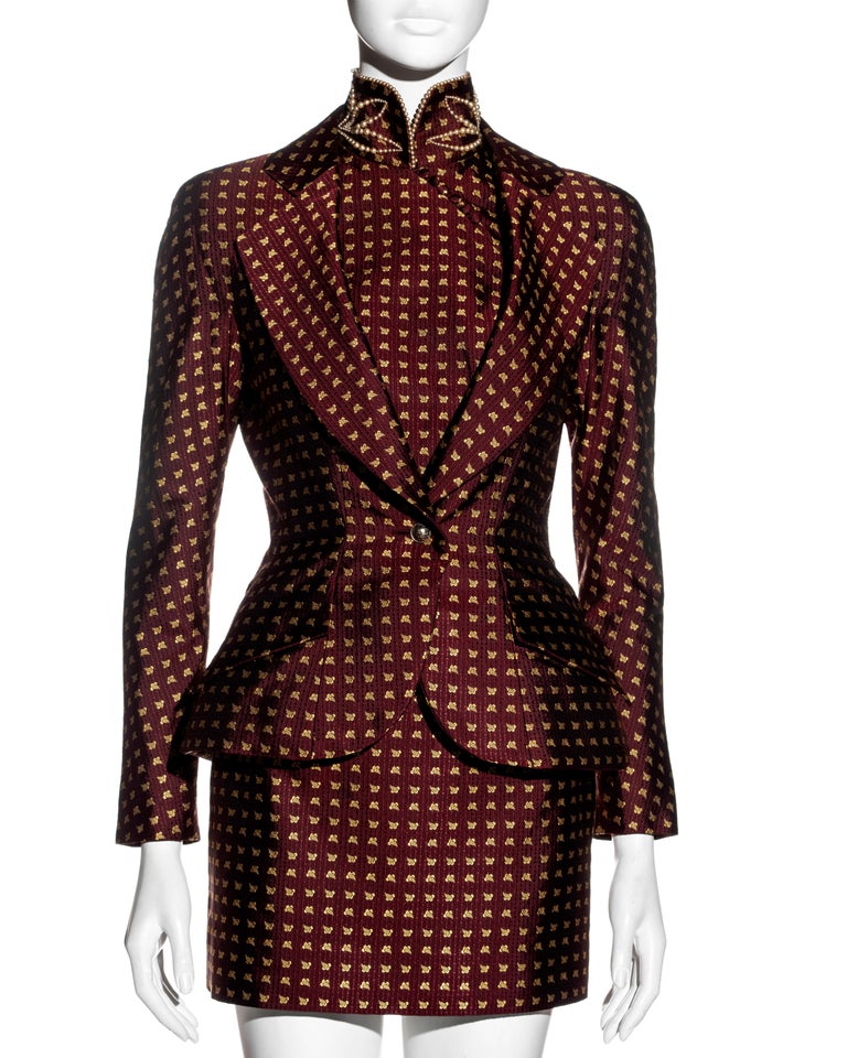 ▪ Christian Dior burgundy jacquard silk micro-mini skirt suit
▪ Designed by John Galliano
▪ Burgundy and gold jacquard silk
▪ Single-breasted jacket with nipped waist
▪ Padded hips 
▪ Mandarin collar with pearl trim 
▪ Built-in shirt front connected