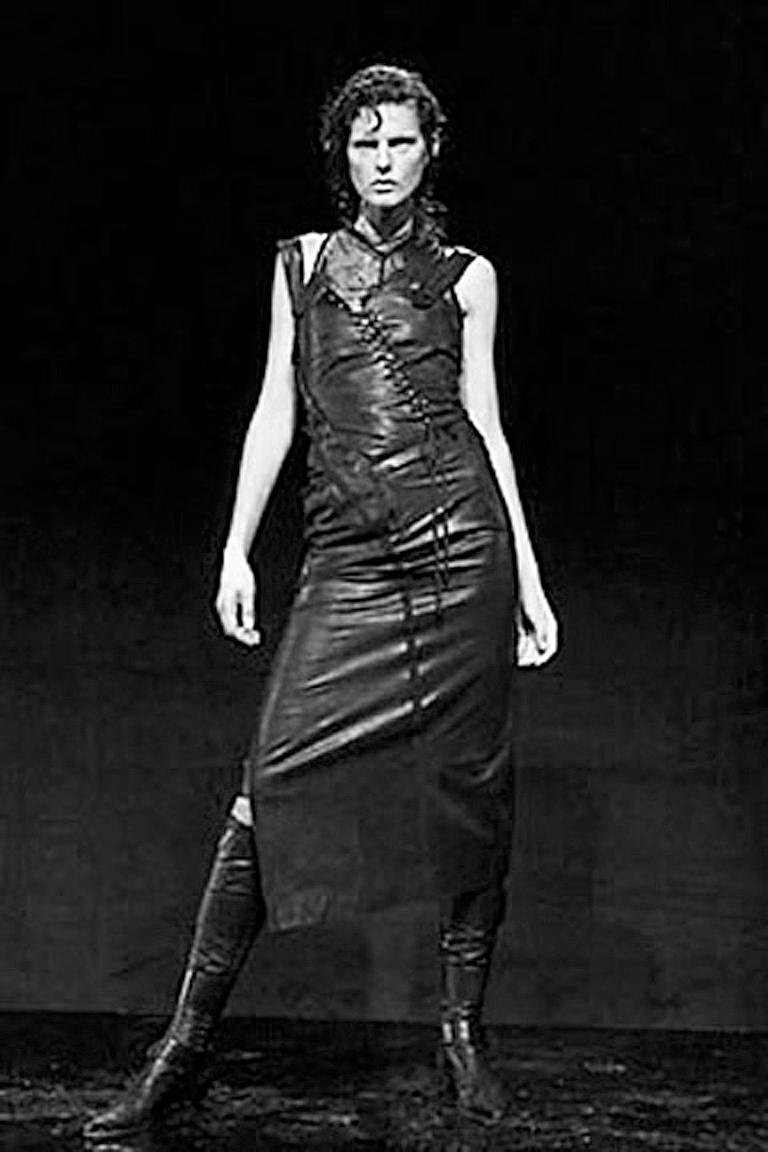 John Galliano's 2000 collection for the House of Dior eighteenth-century inspired asymmetrically cut dress fashioned of black soft lambskin leather. 

Dress features a gathered pulled up bustle style skirt with lace-up bodice and side rubber button