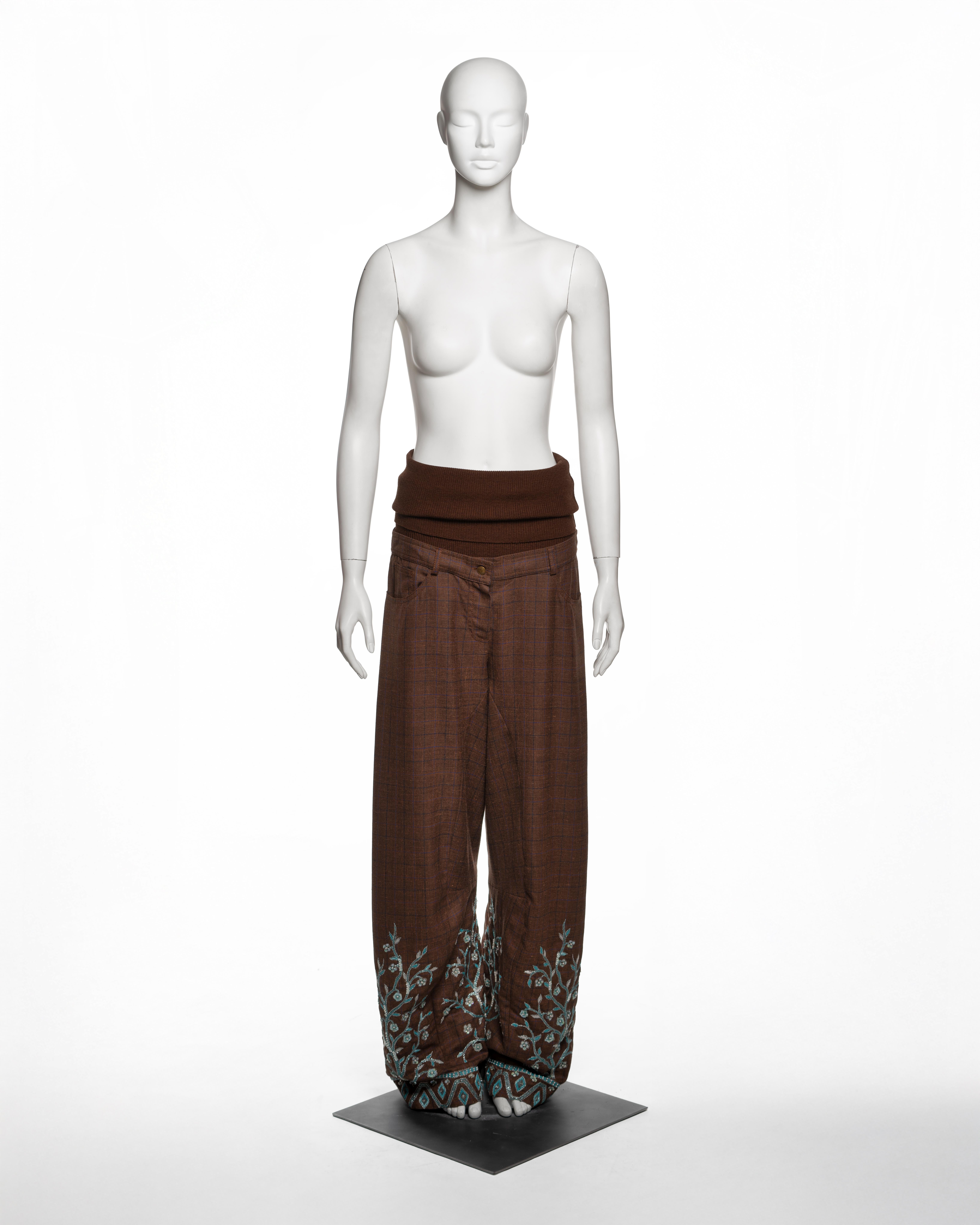 These Christian Dior by John Galliano trousers from the Fall-Winter 2002 collection are tailored from a chestnut brown wool-silk-linen blend with a fine overcheck in navy. The trousers feature a low-rise silhouette with a wide, fold-over waistband