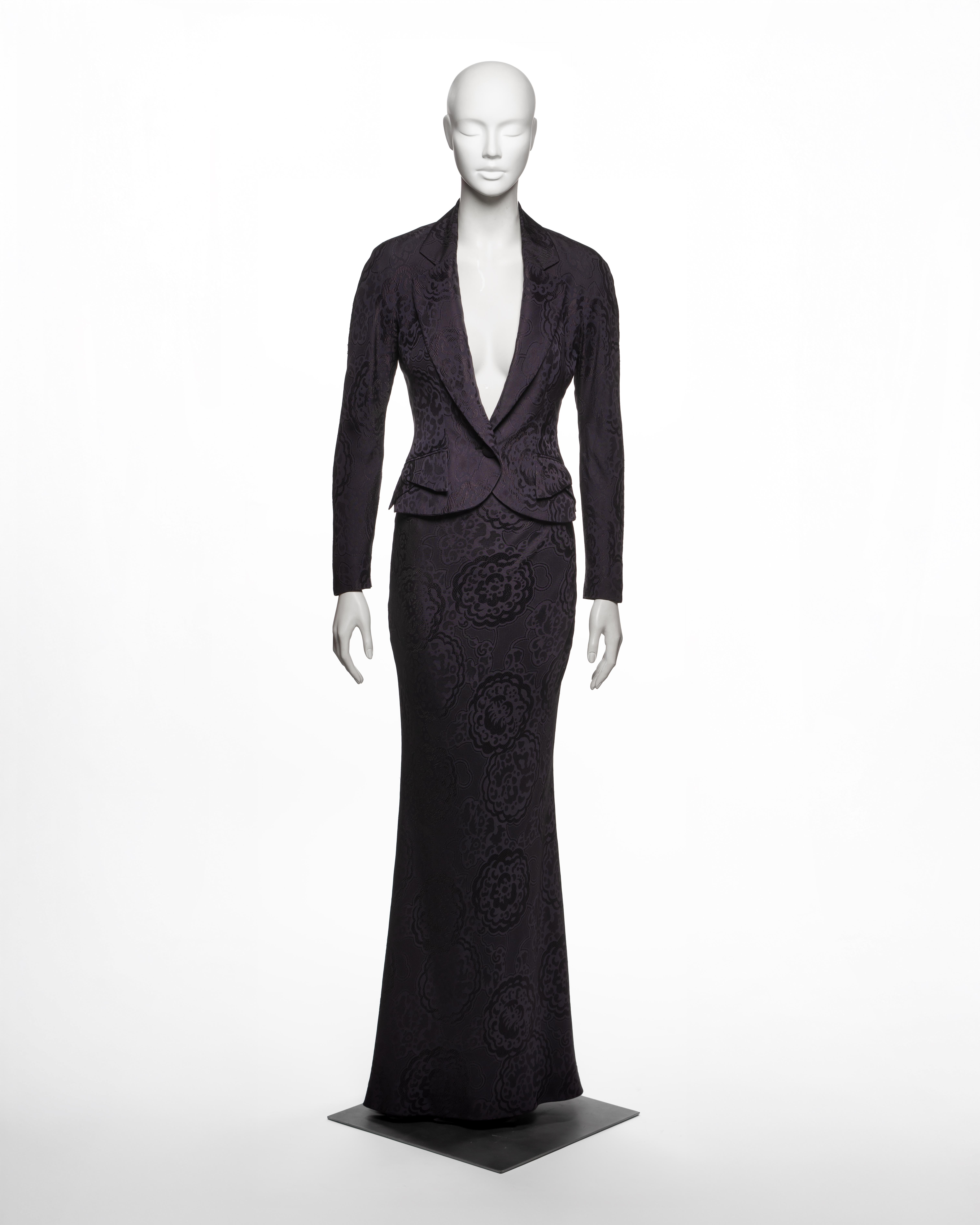 This Christian Dior by John Galliano suit from the Spring-Summer 1999 collection comprises a tailored jacket and a matching floor-length skirt, both executed in dark aubergine silk-blend damask woven with an oversized floral jacquard pattern. The