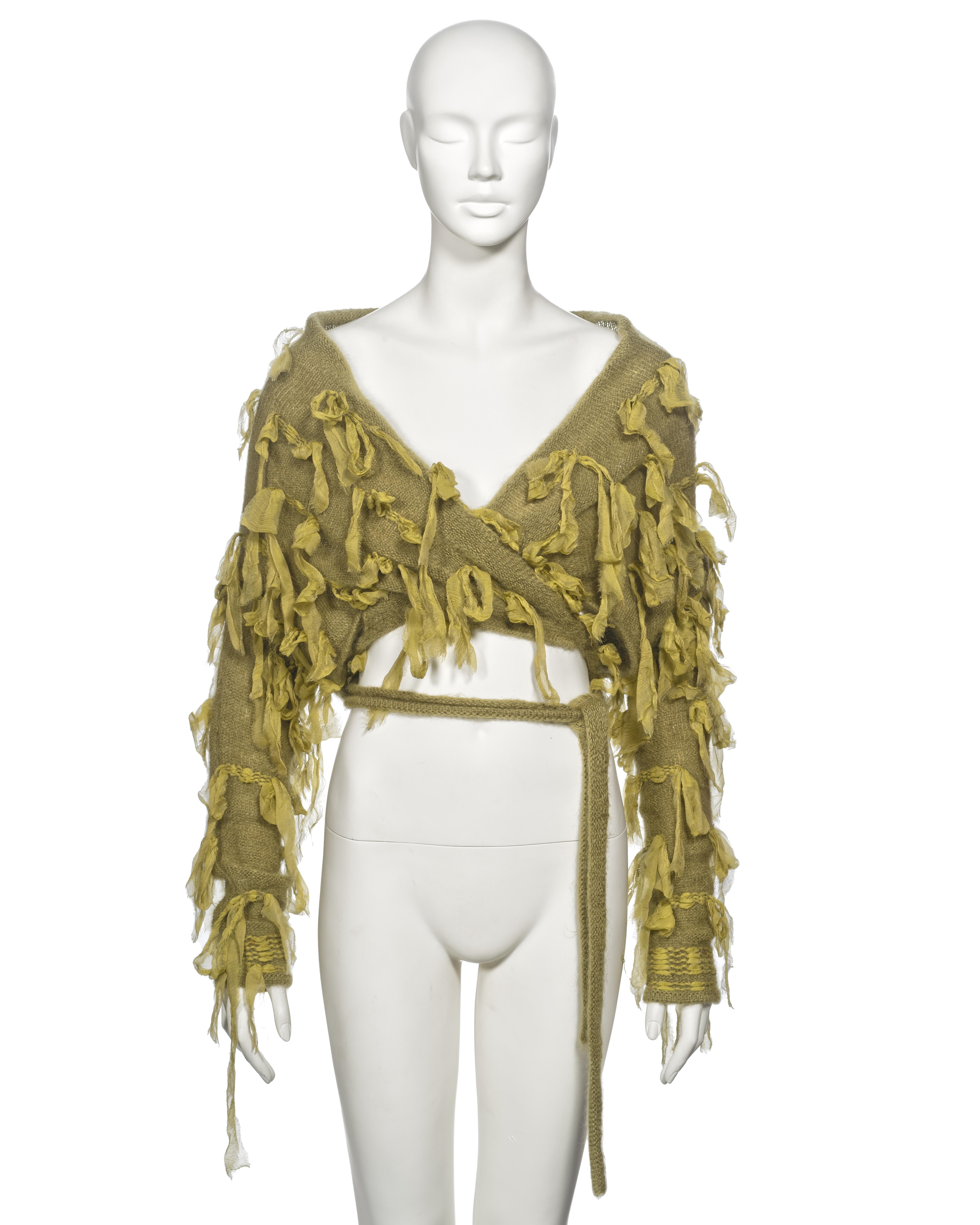 ▪ Archival Christian Dior Cardigan
▪ Creative Director: John Galliano
▪ Fall-Winter 2000
▪ Sold by One of a Kind Archive
▪ Green knitted mohair and wool 
▪ Silk Chiffon knotted ribbon appliques 
▪ Wrap fastening with two long ties 
▪ Can be worn