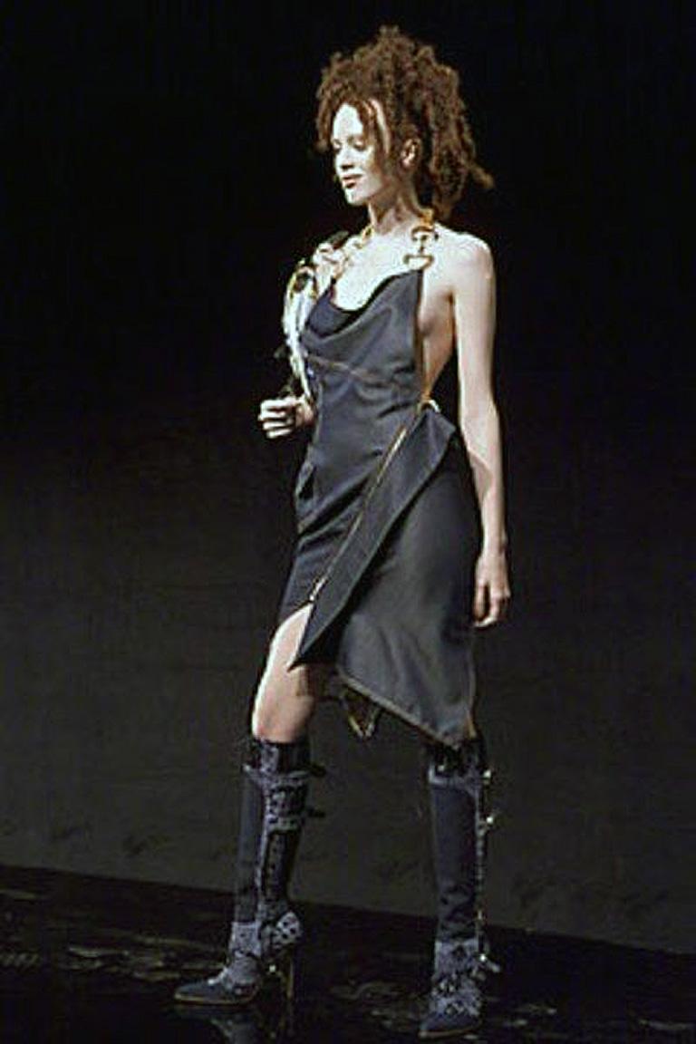 Black Christian Dior by John Galliano early iconic Spring 2000 runway collection featuring cowl neckline halter style dress enhanced by gold-tone logo hardware at straps.  Asymmetrical hem and zipper gold-tone closure at side.  Fully lined.  Rare to