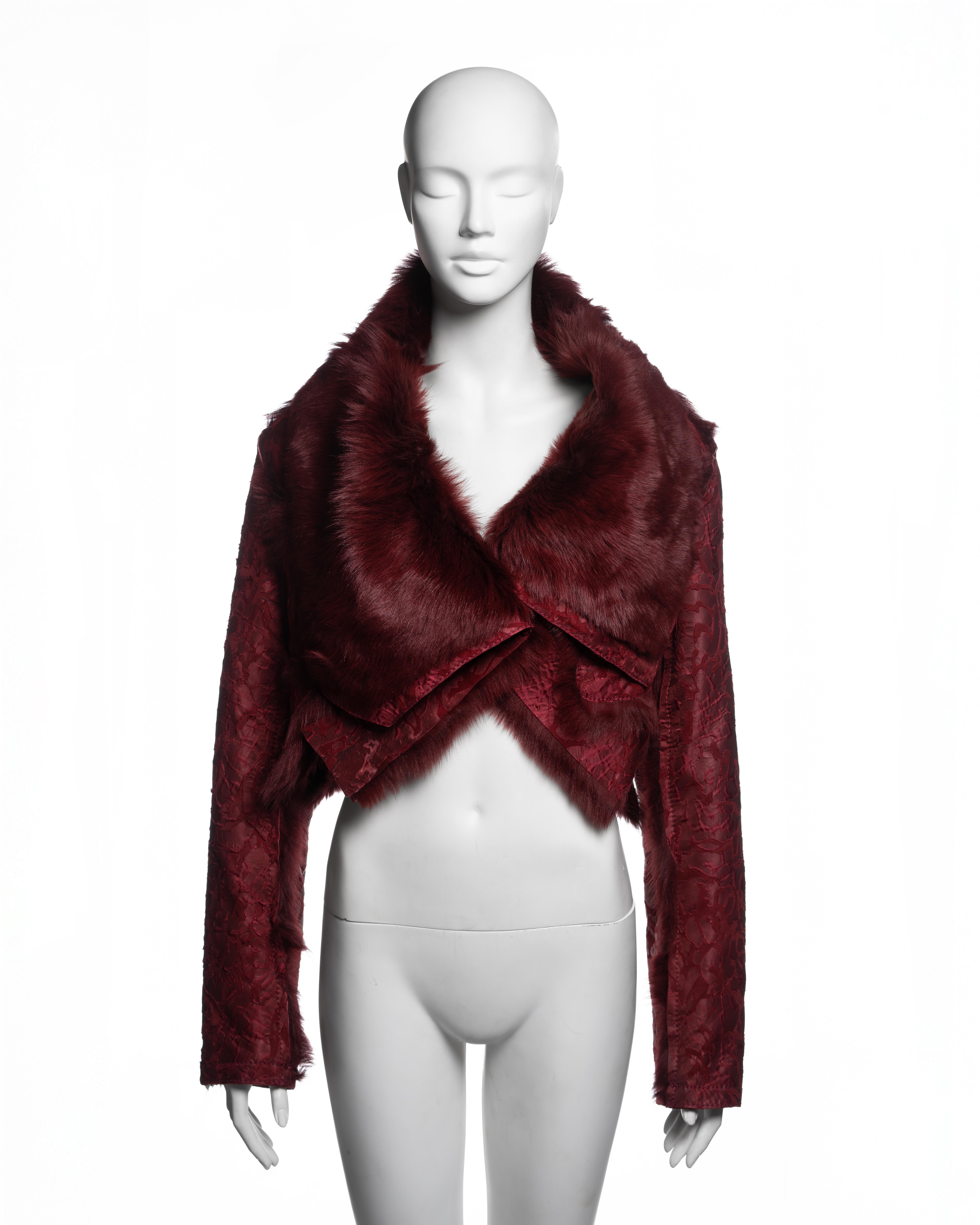 Chaqueta recortada Christian Dior by John Galliano de la colección Otoño-Invierno 2006 en burdeos oscuro. Confeccionada con borreguillo de pelo formando un amplio cuello chal y paneles delanteros superpuestos sobre dobladillos en V en capas; el