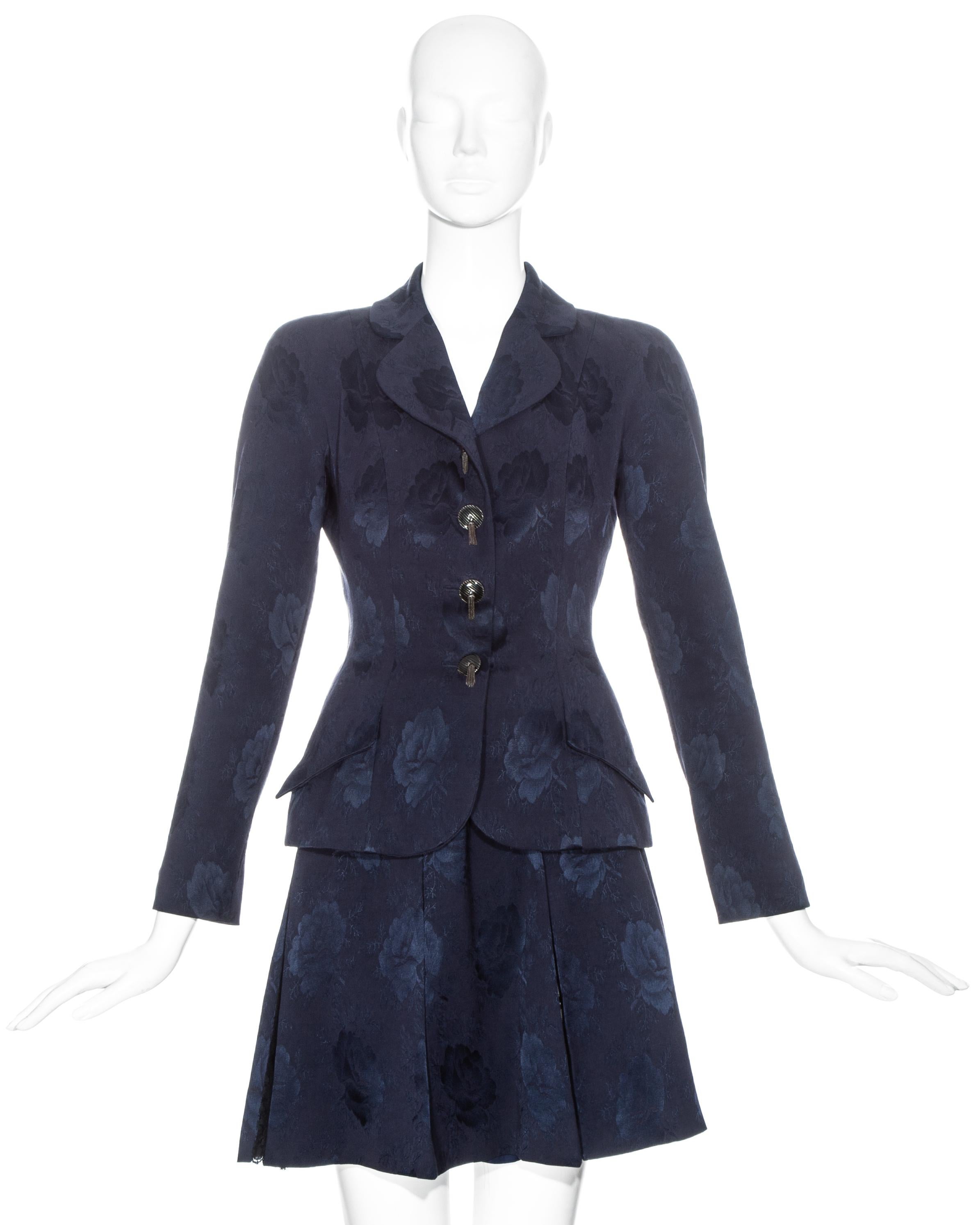 Christian Dior by John Galliano navy floral silk brocade skirt suit comprising: fitted blazer jacket with metal tasseled buttons, two flap pockets and notched lapel, and pleated mini skirt with black lace underlay and zip fastening. 

Fall-Winter