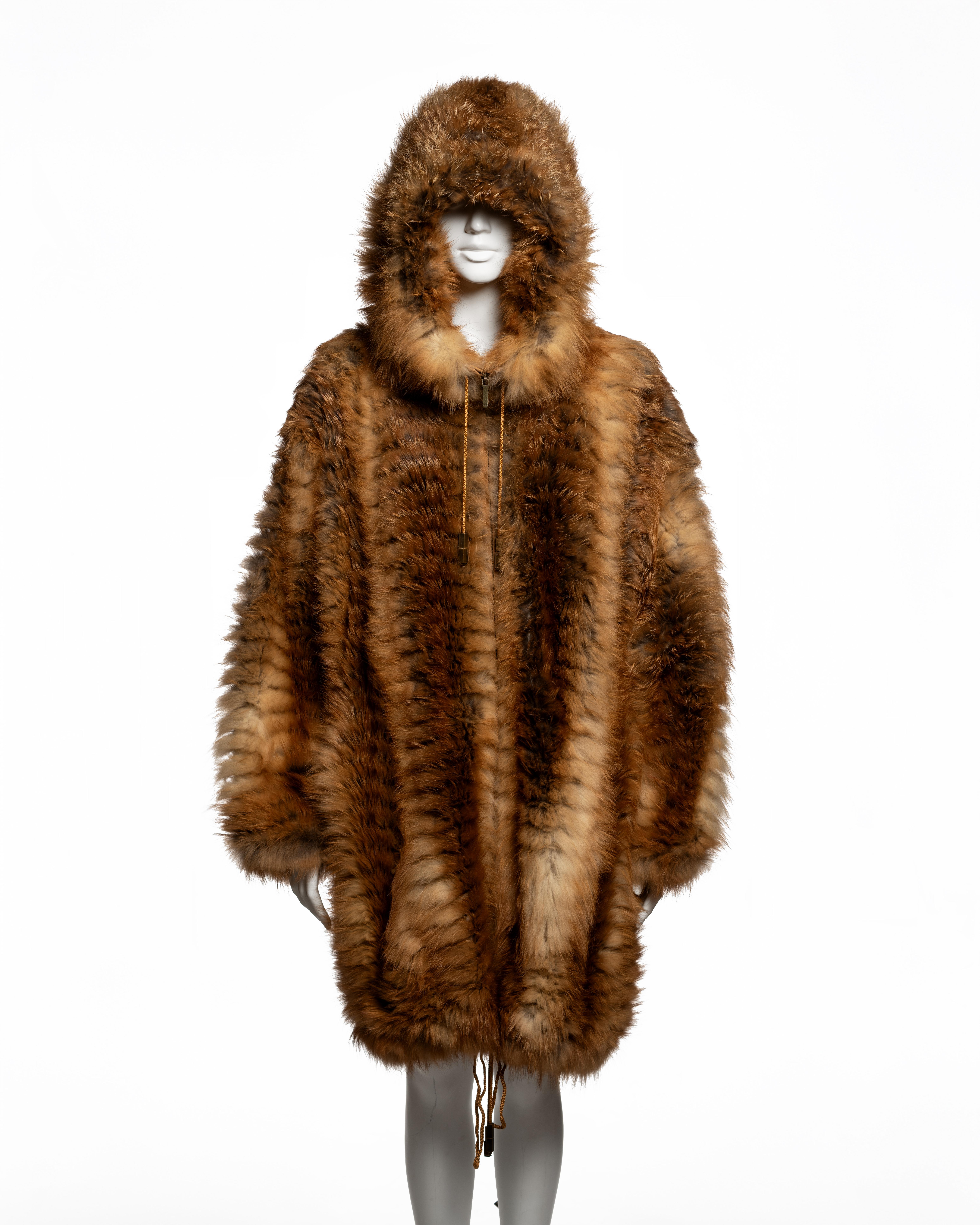 Cappotto con cappuccio di John Galliano for Christian Dior, della collezione Autunno-Inverno 2003, realizzato in pelliccia di volpe rossa naturale a pannelli verticali con fodera in seta tono su tono. La silhouette oversize è realizzata con una