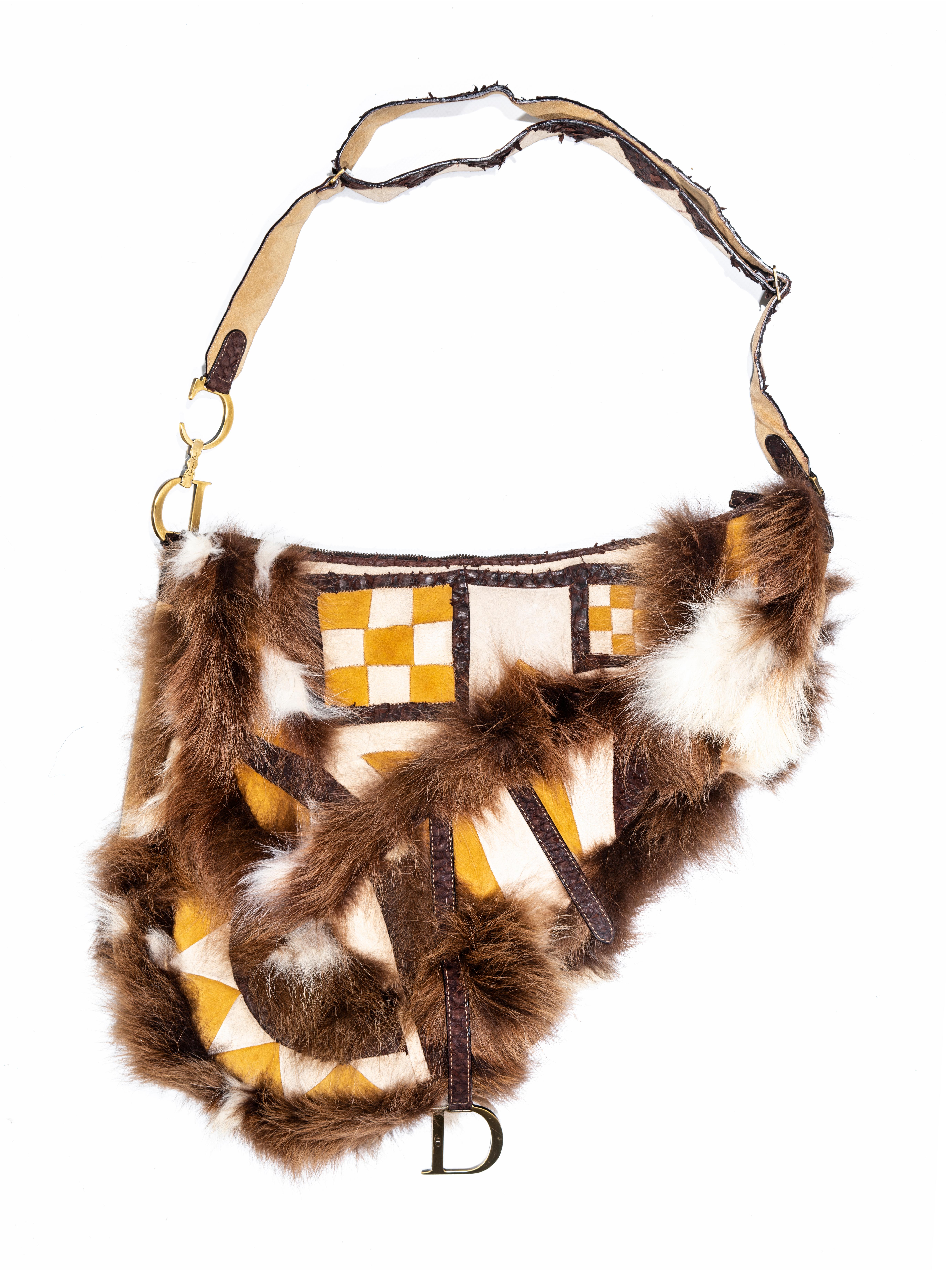 ▪ Christian Dior oversized saddle bag 
▪ Designed by John Galliano 
▪ Cream and yellow patchwork suede 
▪ Brown fur trim 
▪ Brown fish skin trim 
▪ Adjustable shoulder strap 
▪ Gold-finish metal hardware
▪ Saddle flap with a magnetic 'D' stirrup