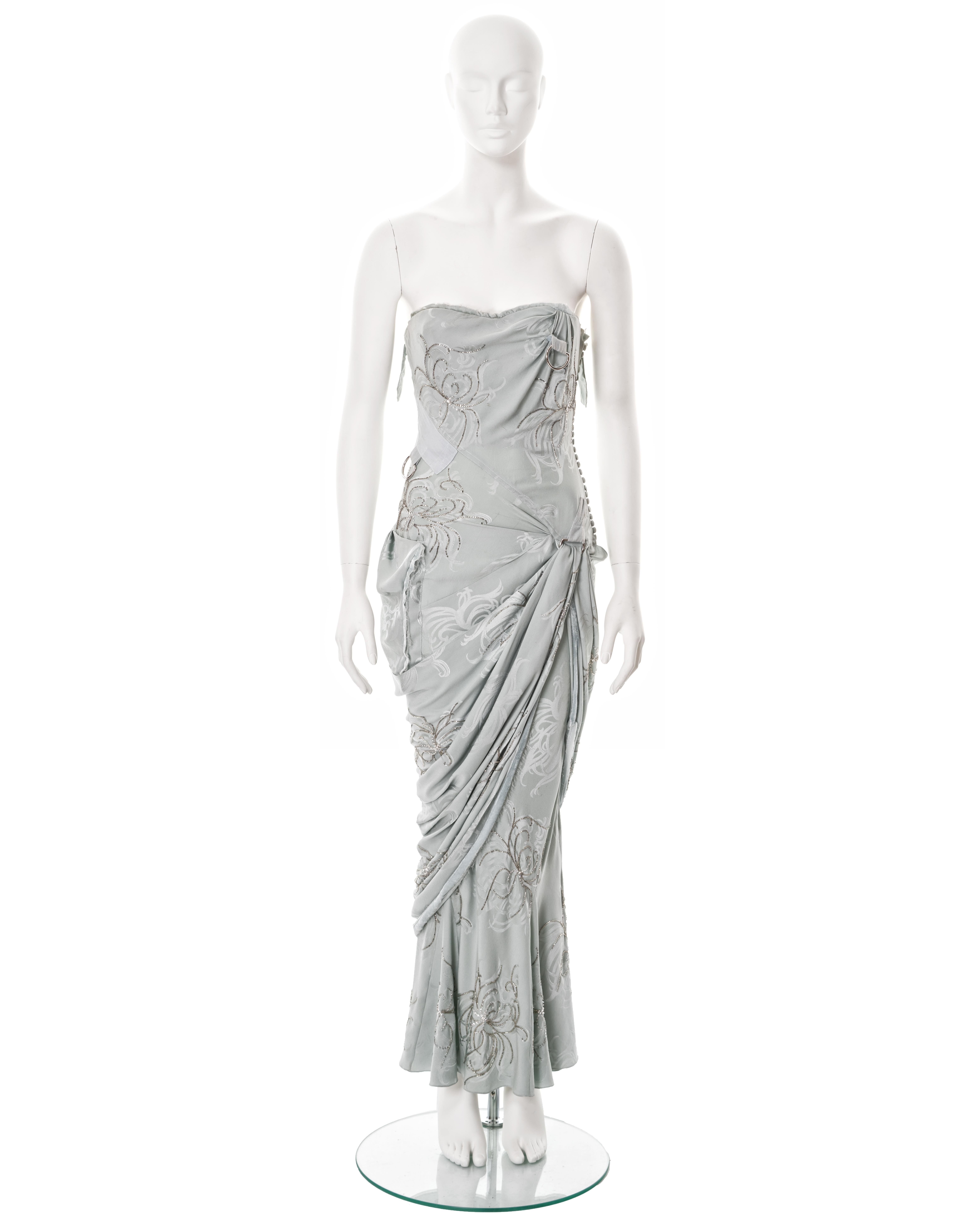 ▪ Christian Dior strapless evening dress
▪ Creative Director: John Galliano
▪ Sold by One of a Kind Archive
▪ Fall-Winter 2005 
▪ Constructed from a pale blue silk damask 
▪ Asymmetric drape skirt 
▪ Silver bugle bead embellishments 
▪ Velvet ribbon