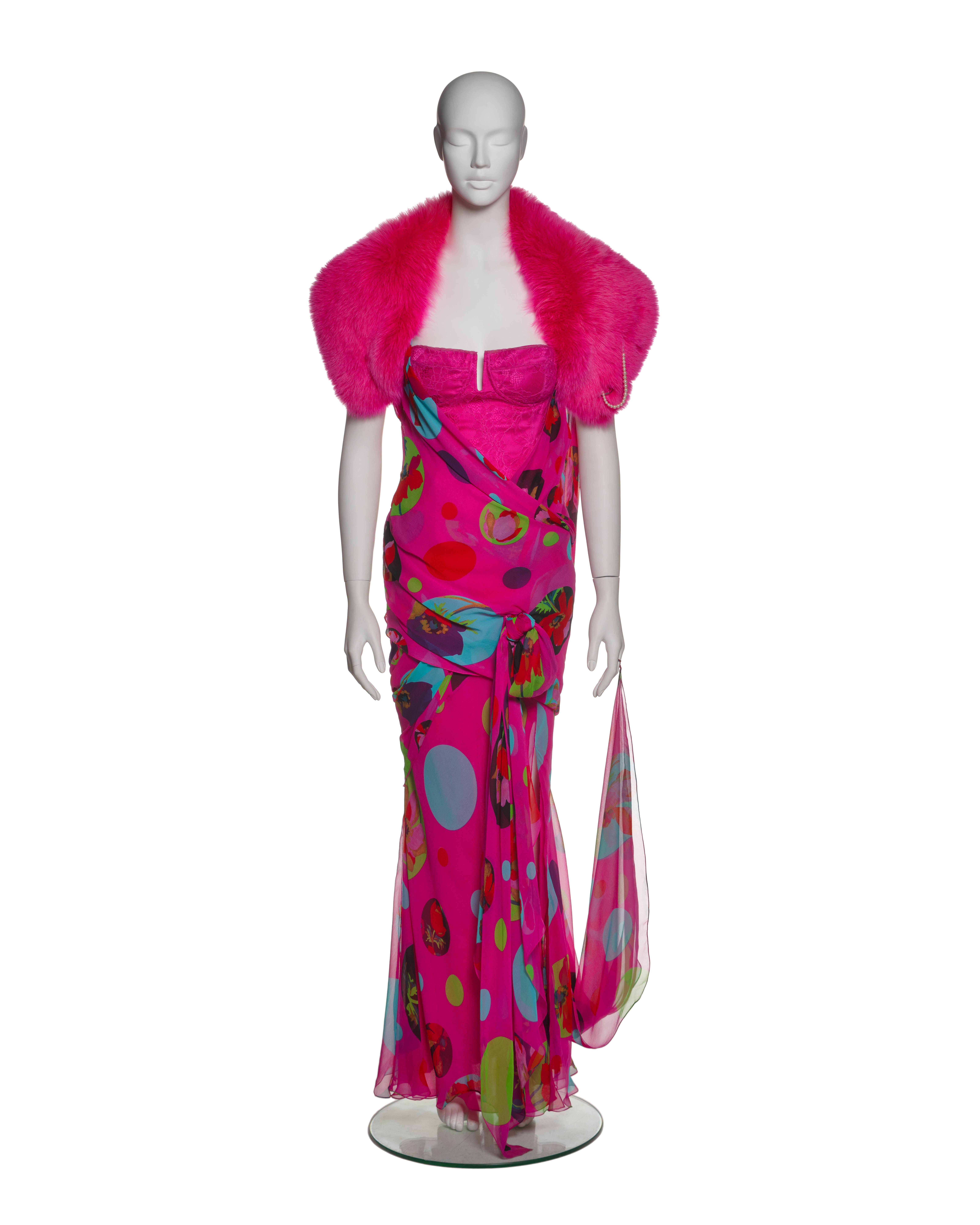 This Christian Dior by John Galliano ensemble from the Spring-Summer 2004 collection includes a vibrant pink chiffon dress, a lace-overlaid corset, and a fox fur bolero/scarf. The dress features spaghetti straps and intricate draping throughout the