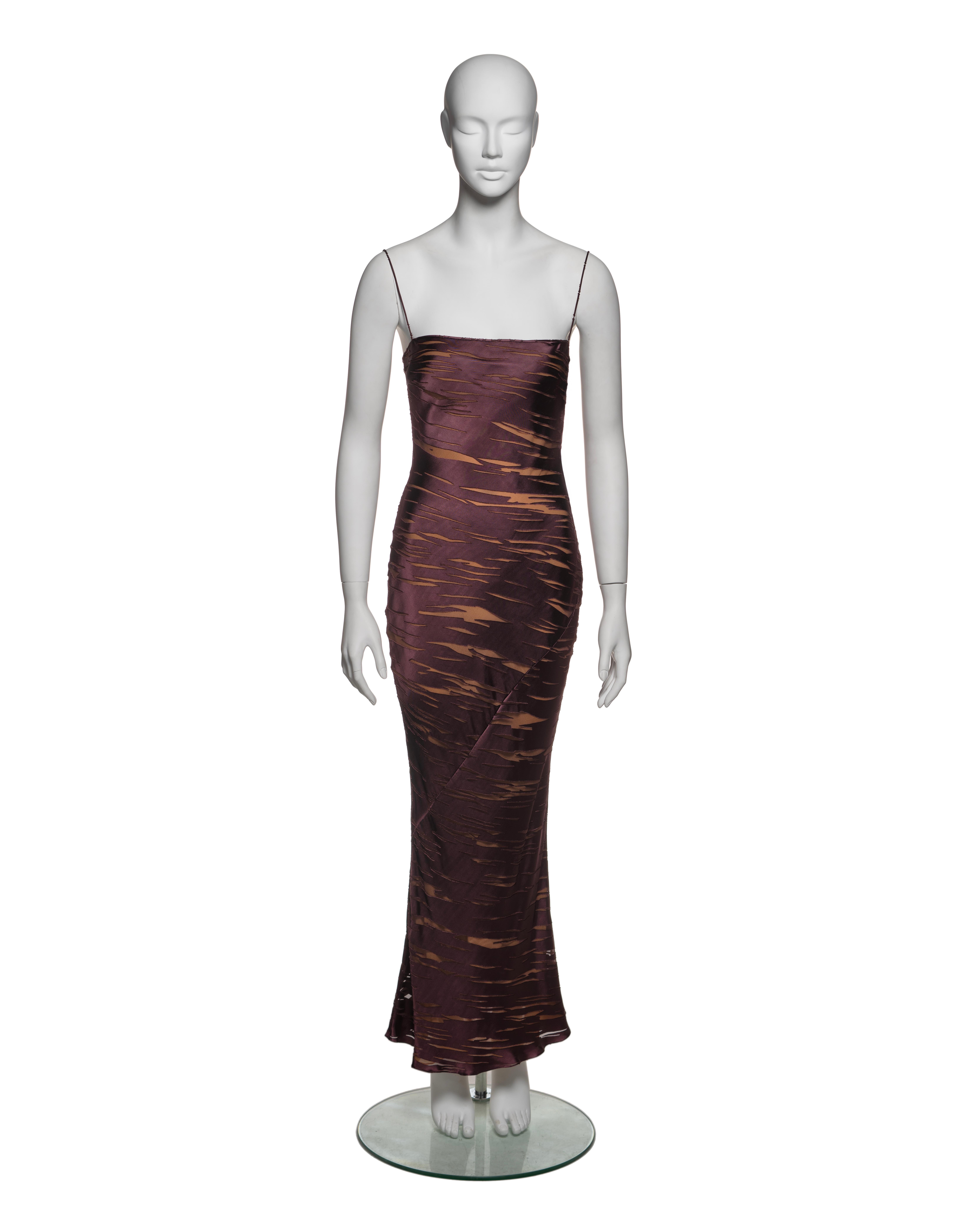 This Christian Dior dress from the Fall-Winter 2000 collection is crafted from viscose-silk devoré fabric in deep plum, featuring semi-sheer sections with a nude silk lining underneath that create a trompe l'oeil effect resembling torn fabric. The