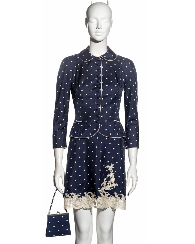 ▪ Christian Dior 3-piece ensemble 
▪ Designed by John Galliano
▪ Navy polka dot silk 
▪ Single-breasted jacket with Peter Pan collar and cream silk trim 
▪ Slip dress edged with cream French lace 
▪ Matching mini bag with metal clasp 
▪ FR 36 - UK 8