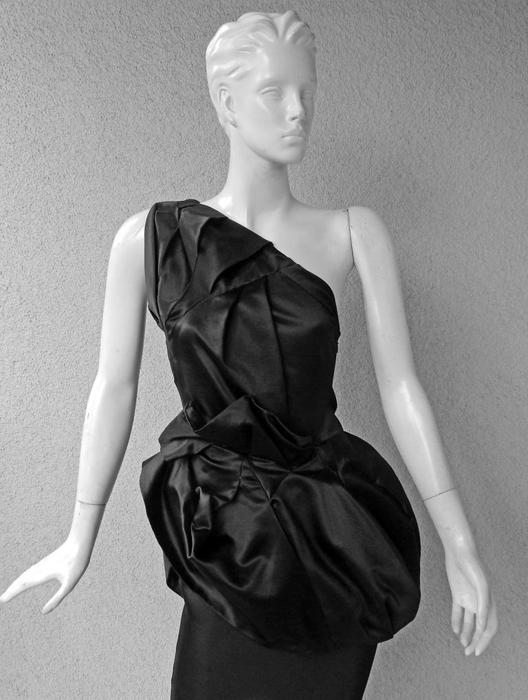 Elegant Christian Dior by John Galliano evening gown.   Circa mid-2000.   Bodice boasts sophisticated hand tailored drape further extended to  peplum at waist.   Extends into long bias cut skirt with godets and train.  Bodice fashioned of black silk