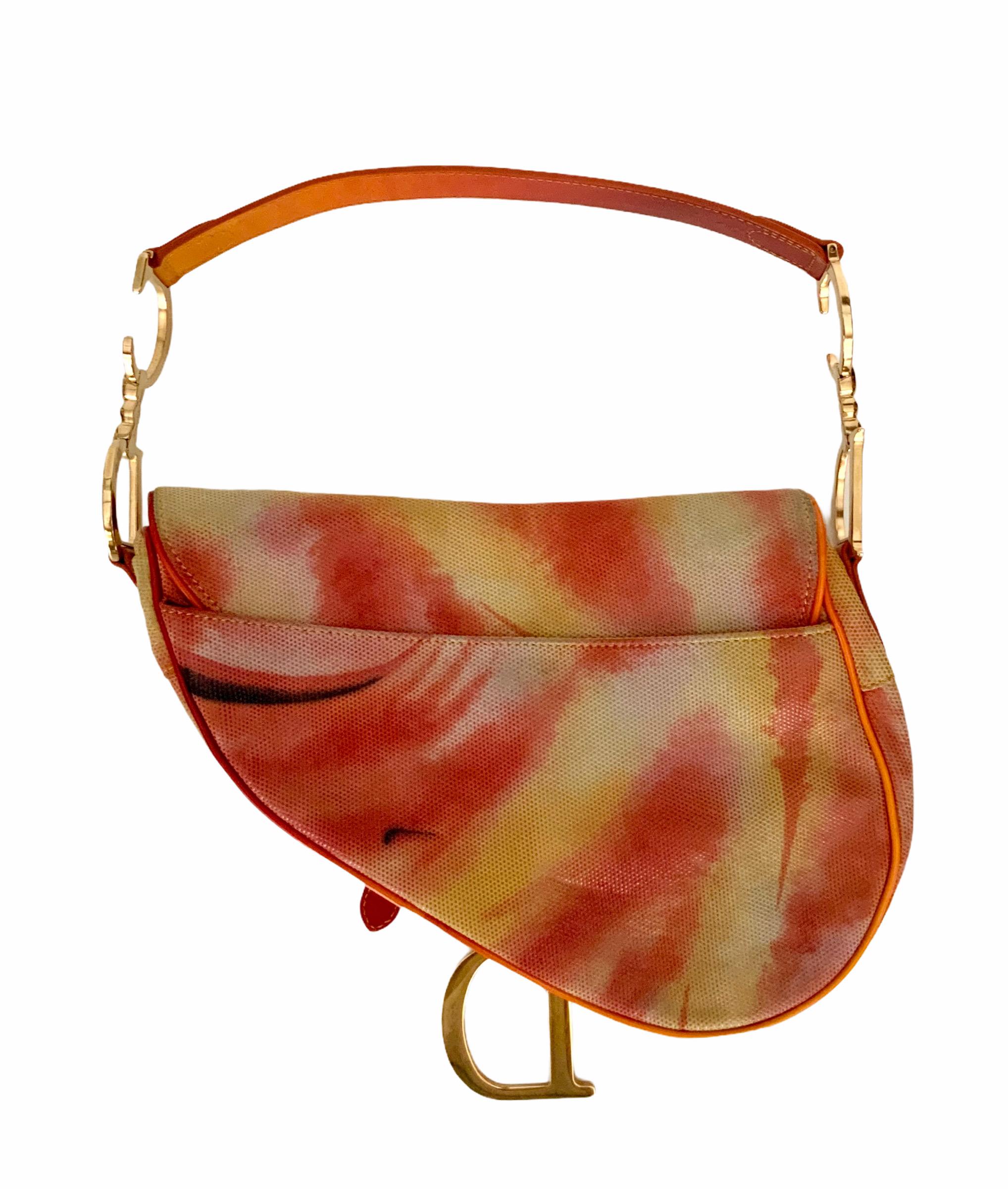 This iconic saddle bag from the house of Christian Dior was designed by John Galliano. 
It is pre-owned but in perfect condition.
It is crafted of shimmering pixelated Tie & Dye orange print leather with patent leather trim.
It features a flat color