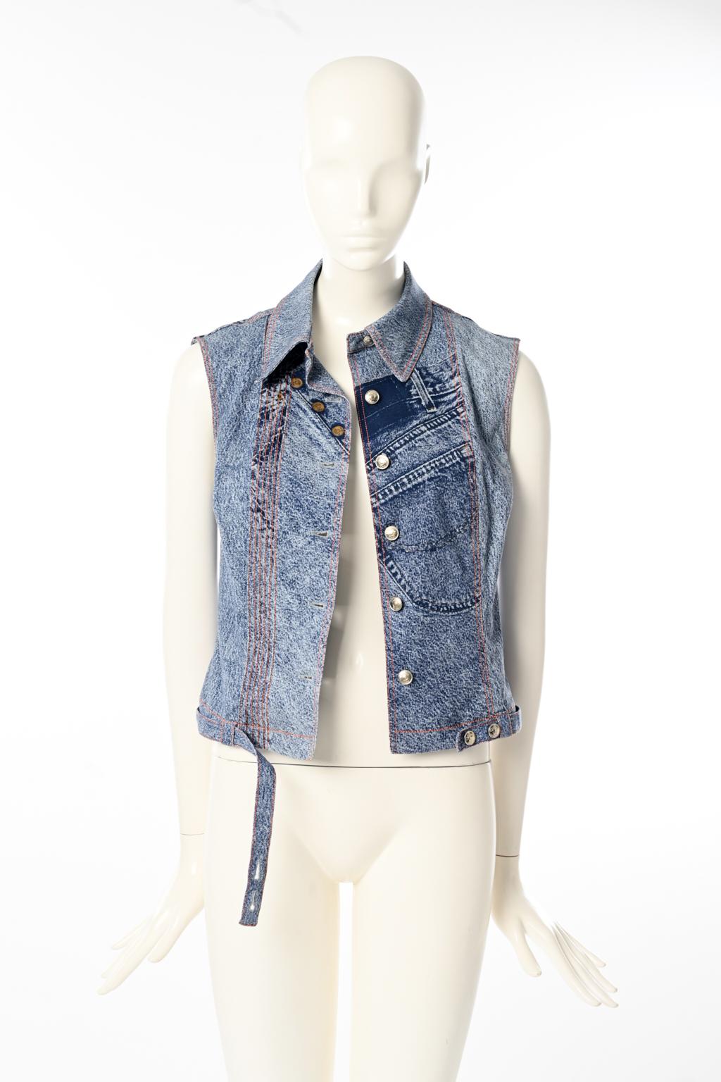 From the unmissable early 2000 John Galliano for Christian Dior collections, this trucker-inspired vest features a “trompe l’oeil” denim. Constructed in cotton with contrasting ochre topstitching, this unlined sleeveless jacket closes with silver