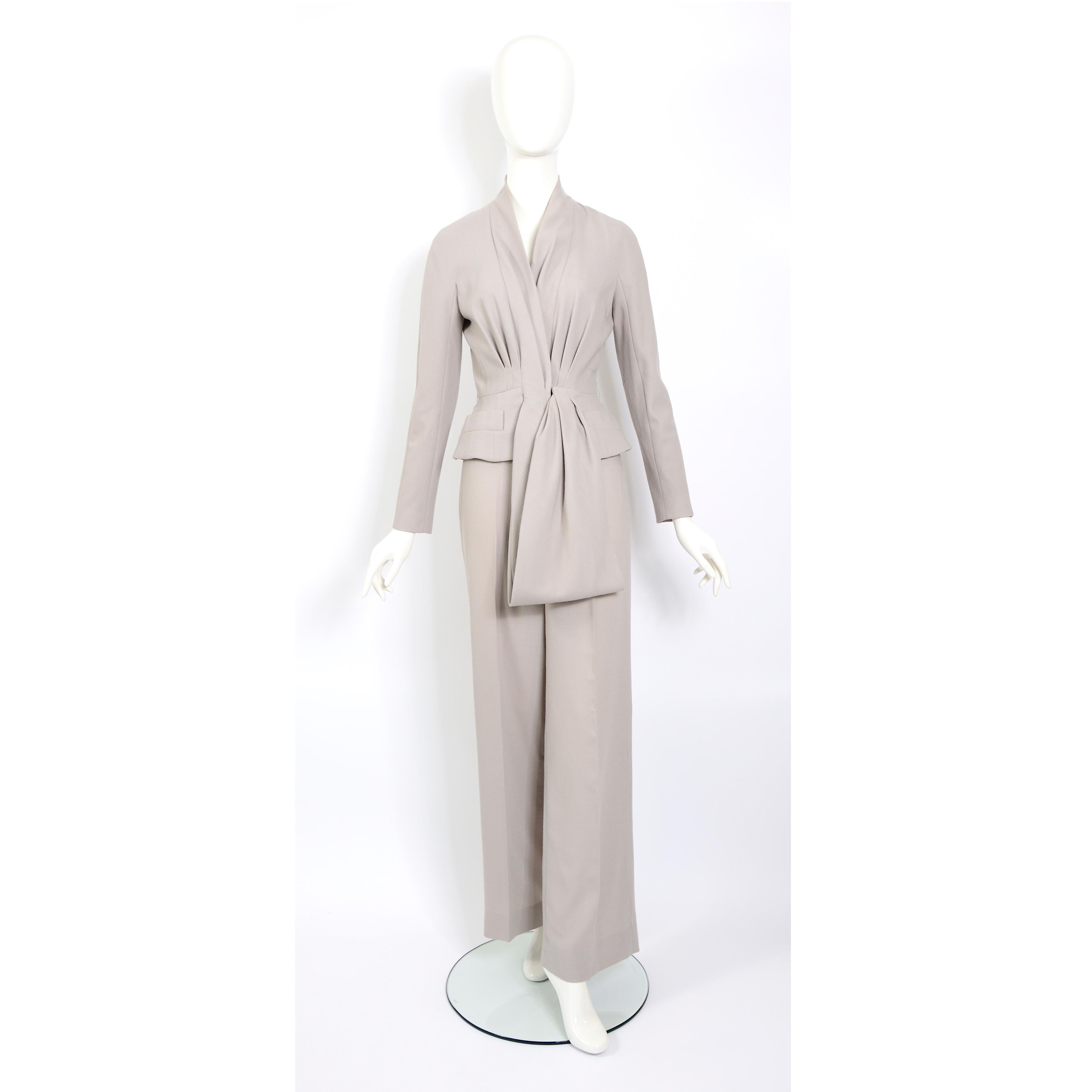 The Christian Dior by John Galliano vintage 2008 ready-to-wear draped waist belt jacket and pants ensemble suit is a stunning piece that embodies the designer's signature style. 
The fully lined jacket is designed with a V-neckline and features a