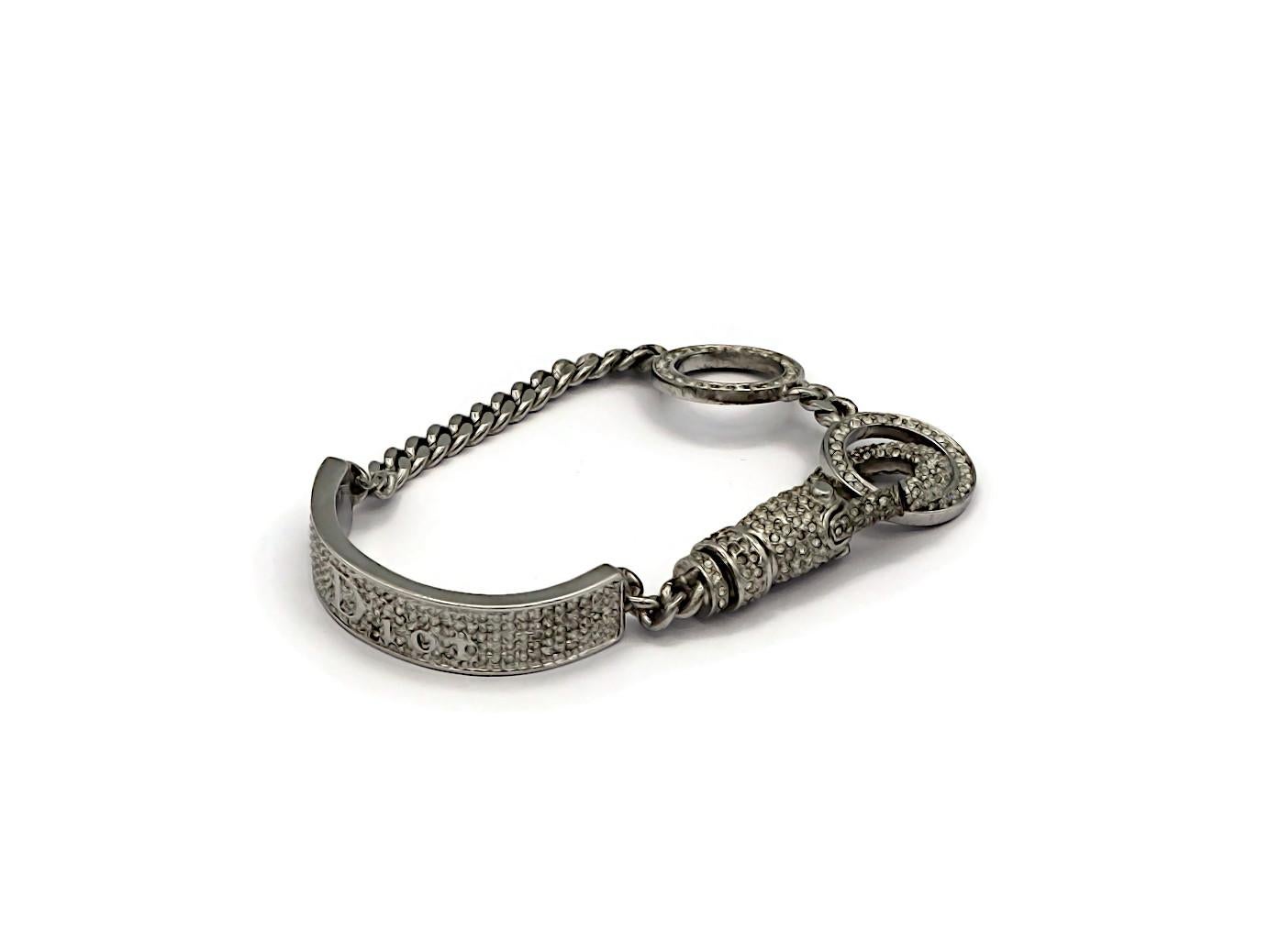 CHRISTIAN DIOR by JOHN GALLIANO Karabinerarmband in Silberton, verziert mit klaren Kristallen.

Geprägte DIOR.

Ungefähre Maße: verstellbare Länge von ca. 14 cm (5,51 Zoll) bis ca. 17 cm (6,69 Zoll)  Zoll) / max. Breite ca. 1,5 cm (0,59
