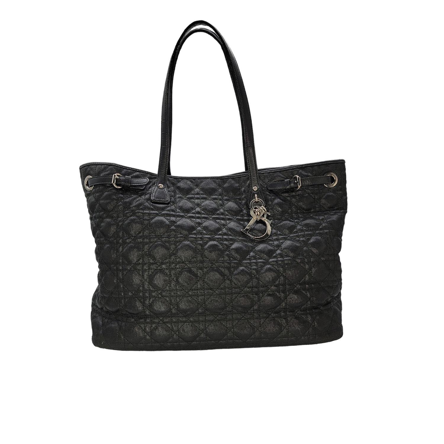 This Christian Dior Cannage Panarea Medium Tote was made in Italy and it is finely crafted of black coated canvas with Cannage pattern embroidery. It features a magnetic snap closure that opens up to a very spacious black canvas interior with one