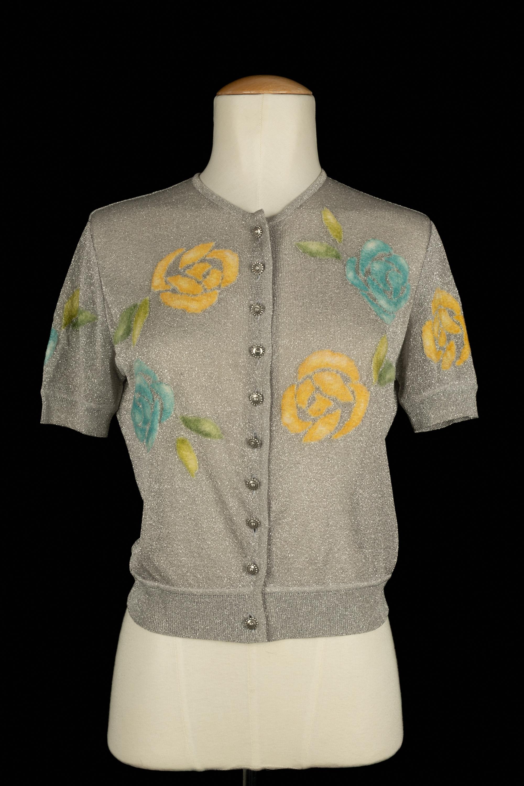 DIOR - Cardigan en fil de lurex argenté à manches courtes, décoré de fleurs jaunes et bleues. Aucune taille n'est indiquée, il convient à un 36FR/38FR. Collection 1998 automne-hiver sous la direction artistique de John Galliano.

Condit :
Bon