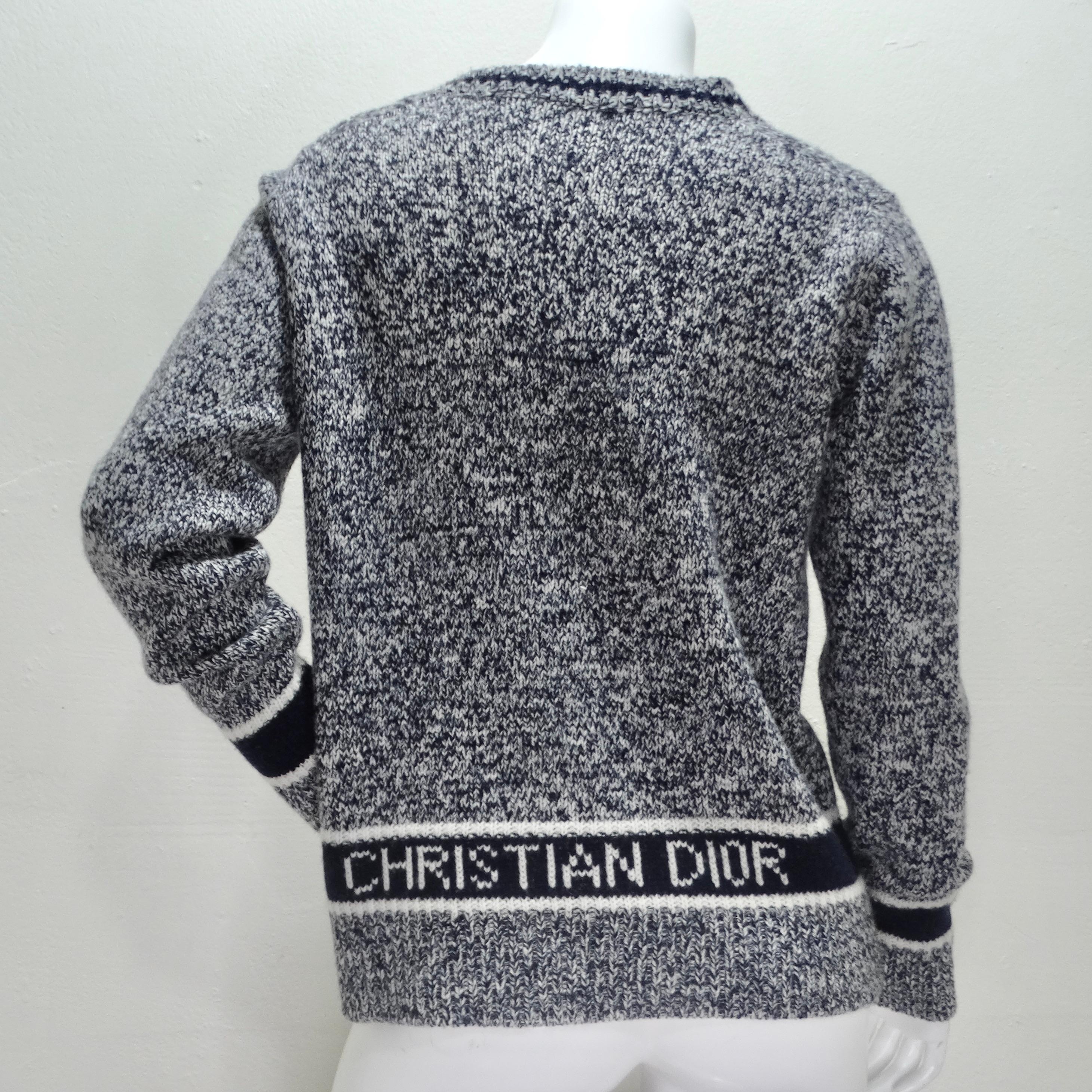 Introducing the Christian Dior Cashmere V-Neck Sweater – a luxurious and timeless piece that exudes sophistication and style. Crafted from a white and navy specked knit blend of cashmere and wool, this sweater offers both warmth and comfort with a