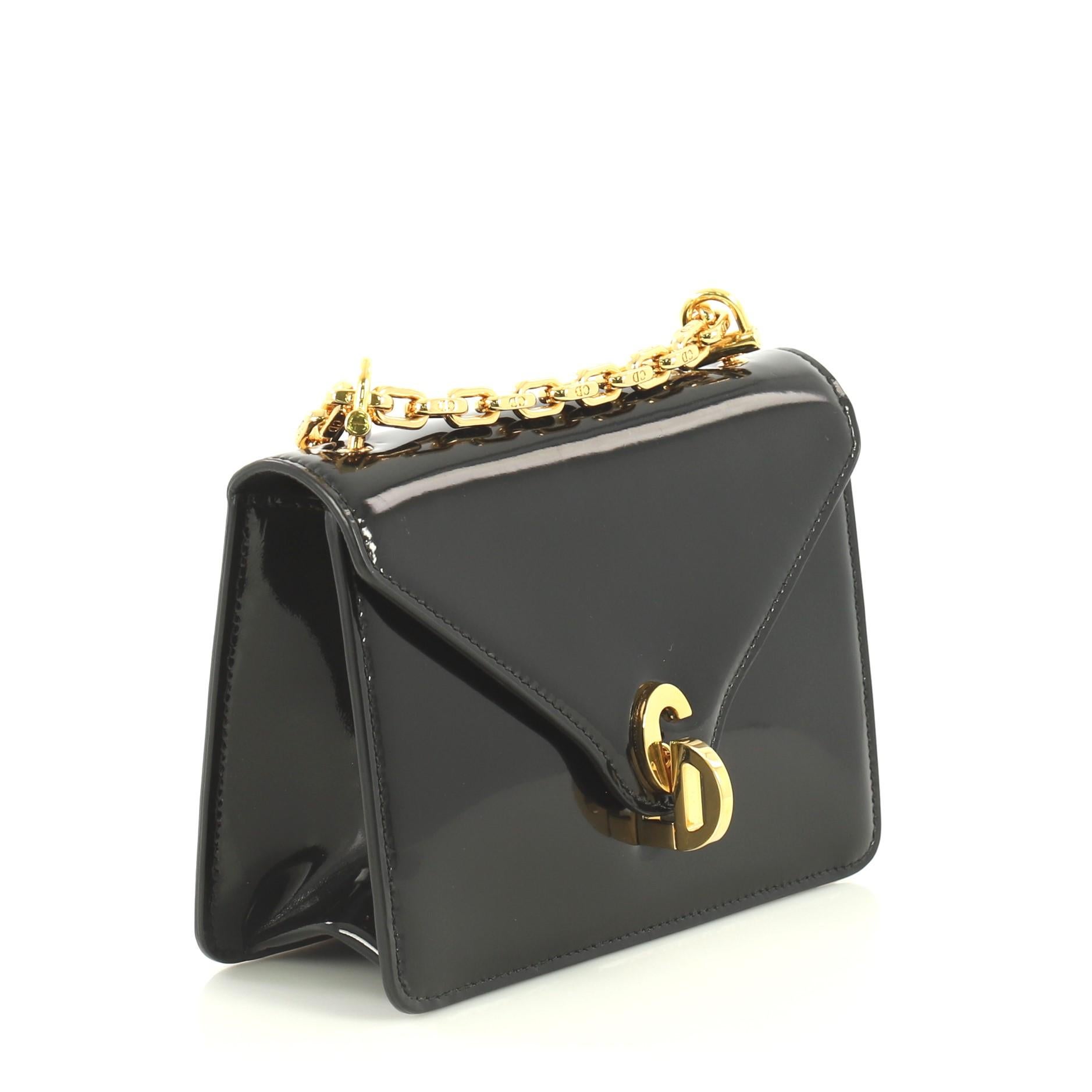 This Christian Dior C'est Dior Flap Bag Patent Mini, crafted in black patent leather, features chain link shoulder strap, front flap with CD twist lock and gold-tone hardware. Its twist-lock closure opens to a black suede interior with zip pocket.