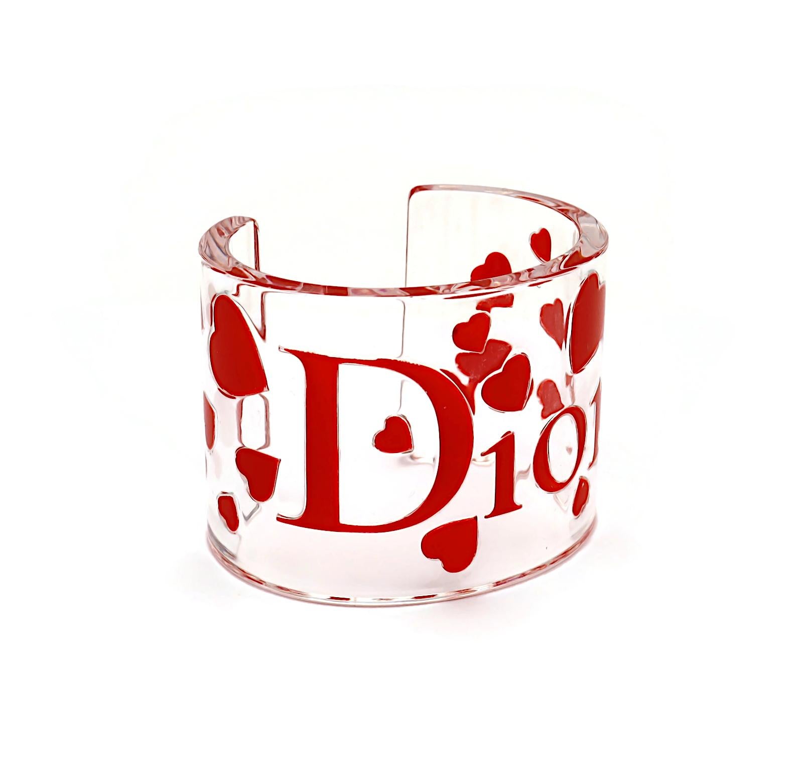 CHRISTIAN DIOR Manschettenarmband aus klarem Harz mit rosa Herzen und D I O R Logo.

Unmarkiert.

Ungefähre Maße: Innenmaße ca. 6,4 cm x 4,5 cm (2,52 Zoll x 1,77 Zoll) / Breite ca. 5,6 cm (2,20 Zoll) / Manschettenöffnung ca. 3,2 cm (1,26