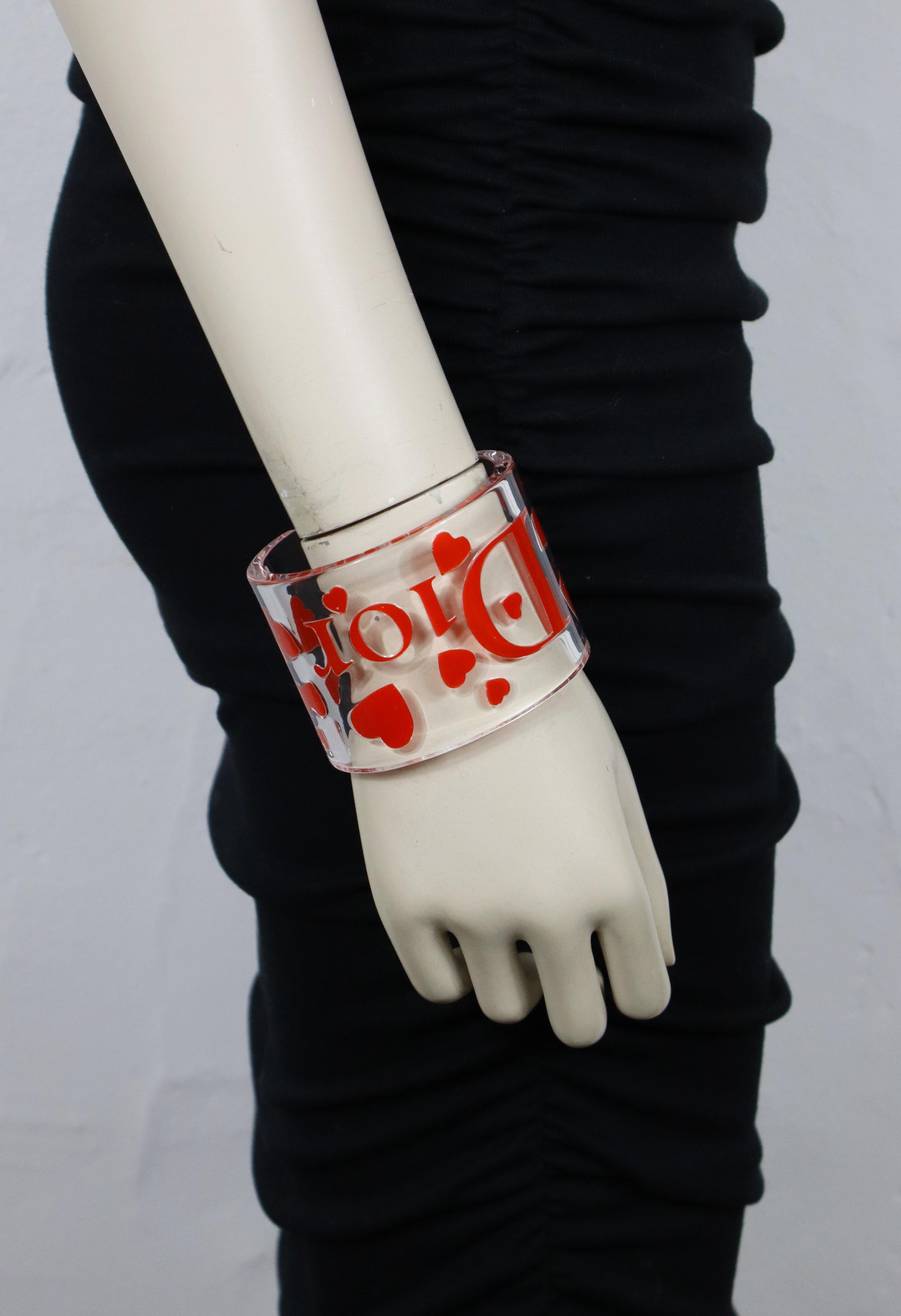 Bracciale CHRISTIAN DIOR in resina trasparente con cuori rosa e logo D. A.

Non segnato.

Misure indicative: misure interne circa 6,4 cm x 4,5 cm (2,52 pollici x 1,77 pollici) / larghezza circa 5,6 cm (2,20 pollici) / apertura del polsino circa 3,2