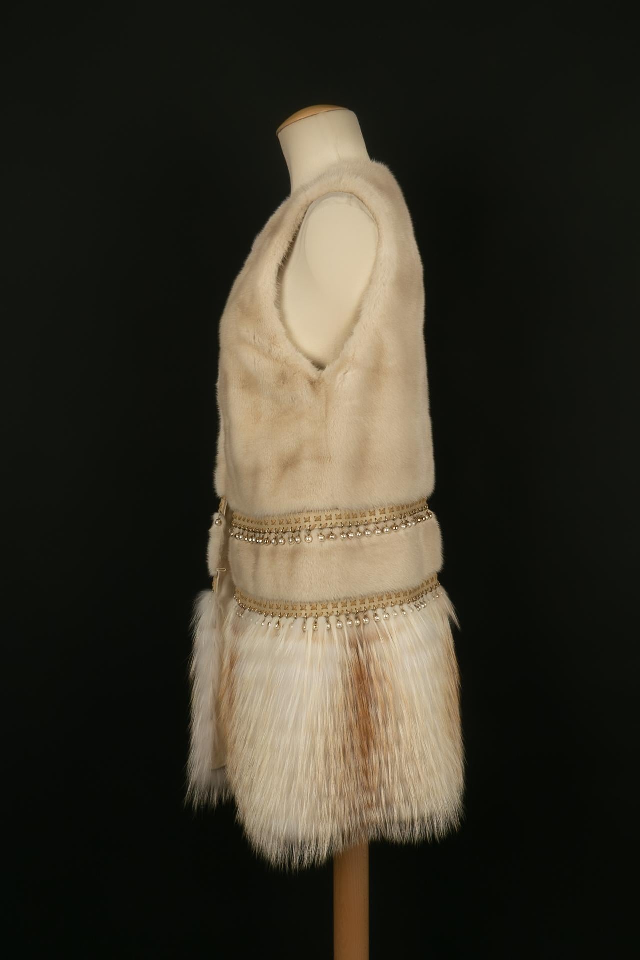 DIOR - (Made in France) Sleeveless coat in sand mink, horizontal work interspersed with leather and pearl strips. The bottom of the garment is made of fox on leather inserts. No size indicated, it fits a 38FR/40FR.
Clothing from the 2010s.