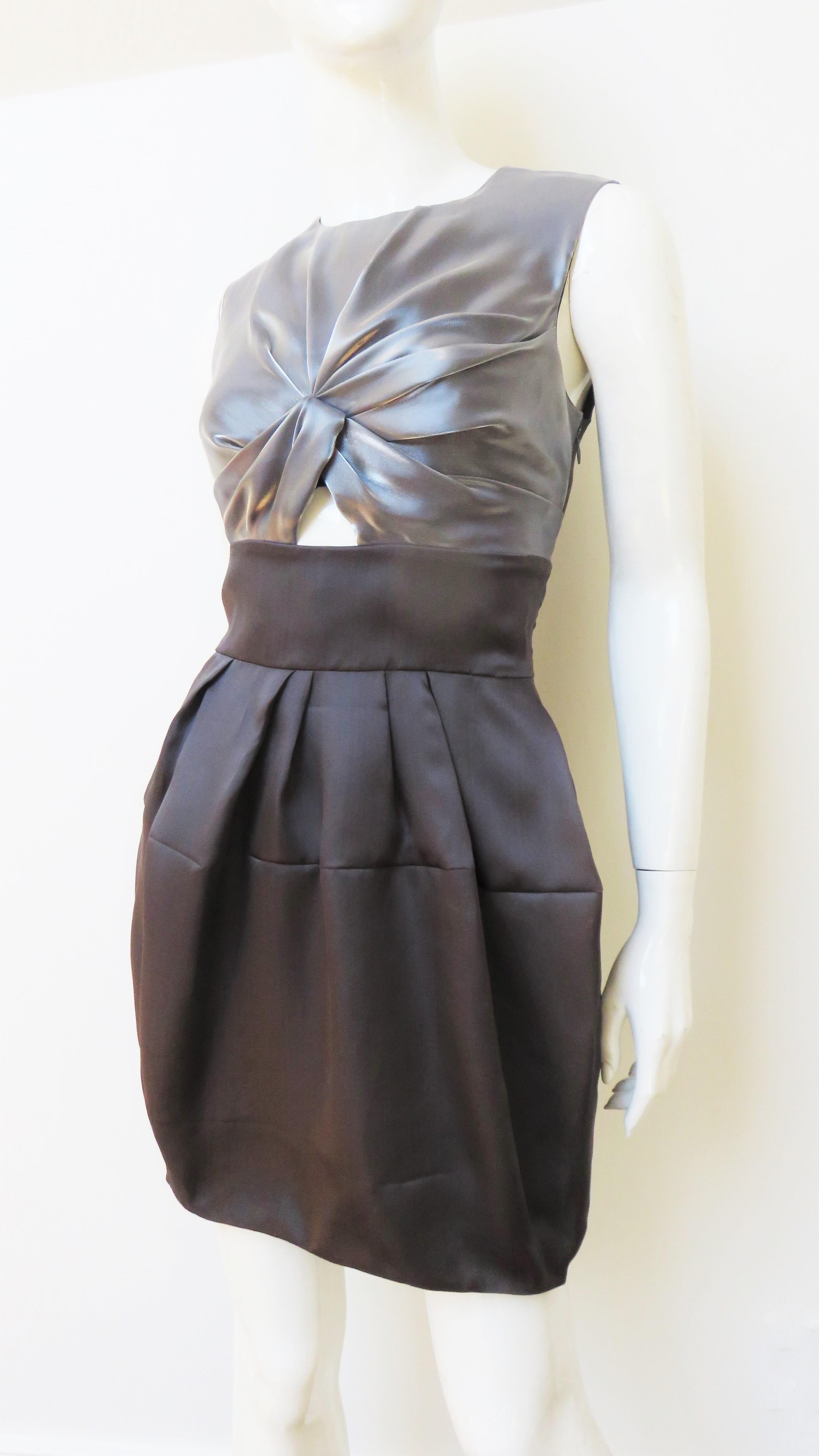 A fabulous grey and silver silk dress from Christian Dior.  It is sleeveless with a crew neckline and a ruched silver front bodice with a cut out.  The grey skirt has hip side seam pockets and is fuller at the top, narrowing towards the hem. The