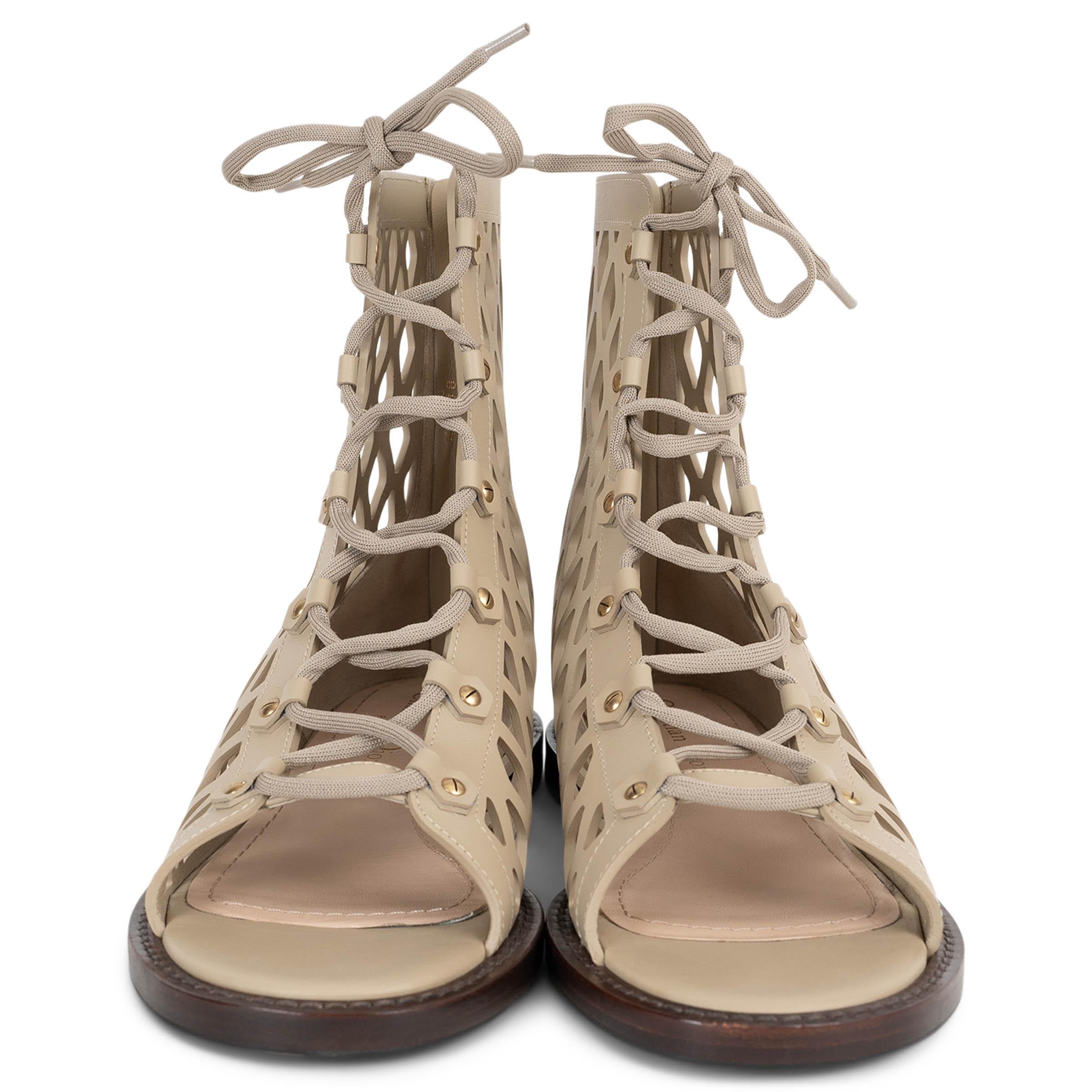 Diese 100% authentischen Christian Dior D-Trap Gladiatorensandalen sind aus mattem Kalbsleder in Corde Beige gefertigt und haben ein auffälliges, lasergeschnittenes Obermaterial aus Fischnetz. Sie haben einen knöchelhohen Schaft und eine Schnürung