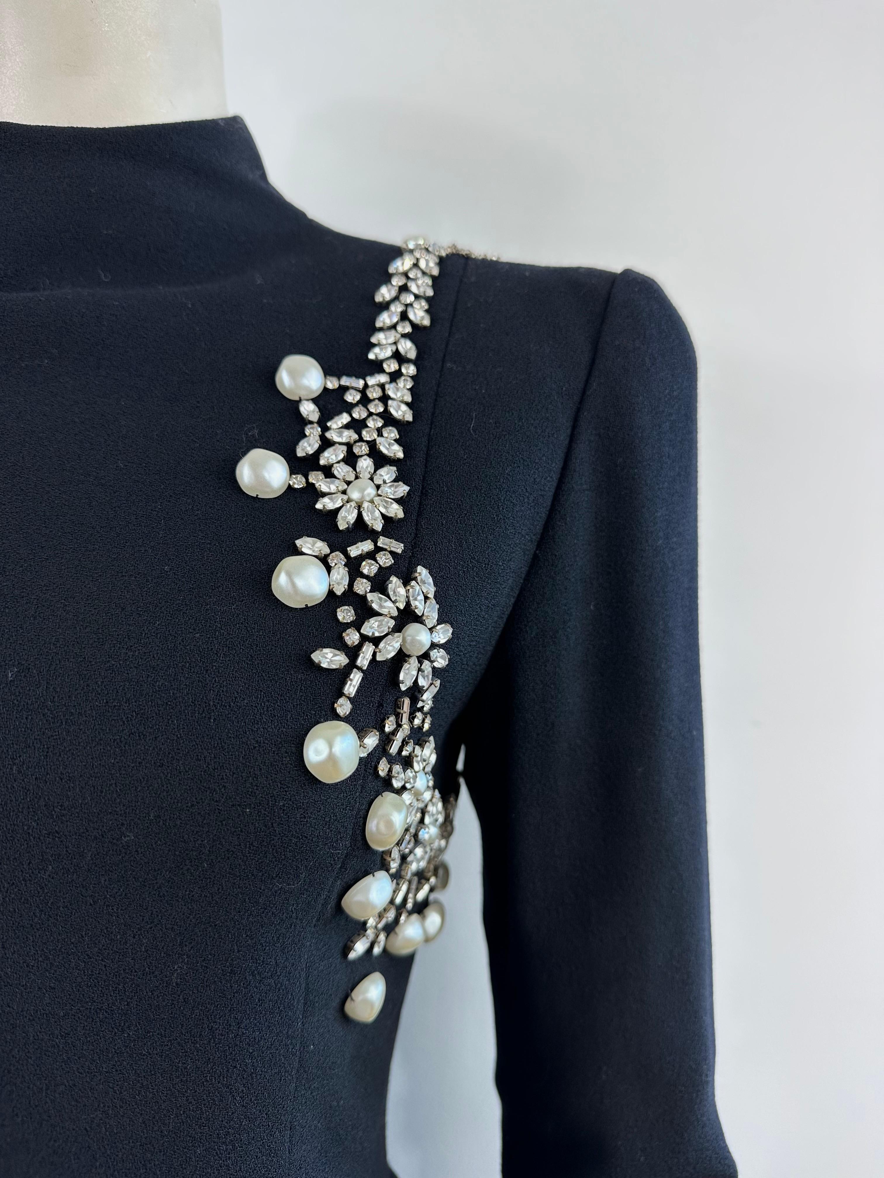 Christian Dior by Marc Bohan F/W 86/87 robe en crêpe mousse noir avec une guirlande de strass et de perles autour de la manche gauche.
Robe fourreau ajustée avec col montant et manches longues avec poignets zippés.
Longue fermeture éclair au dos se
