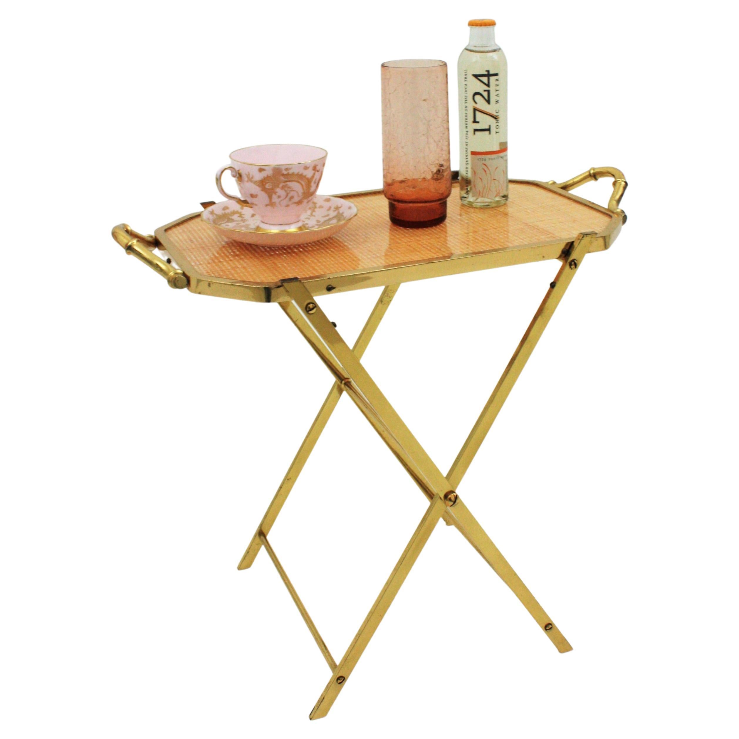 Dior Home  faux bamboo brass and rattan folding tray table, France, 1970s.
This cocktails table or drinks table features an X-base folding stand with a serving tray comprised of a sheet of Lucite with embedded woven rattan/cane work in an octogonal
