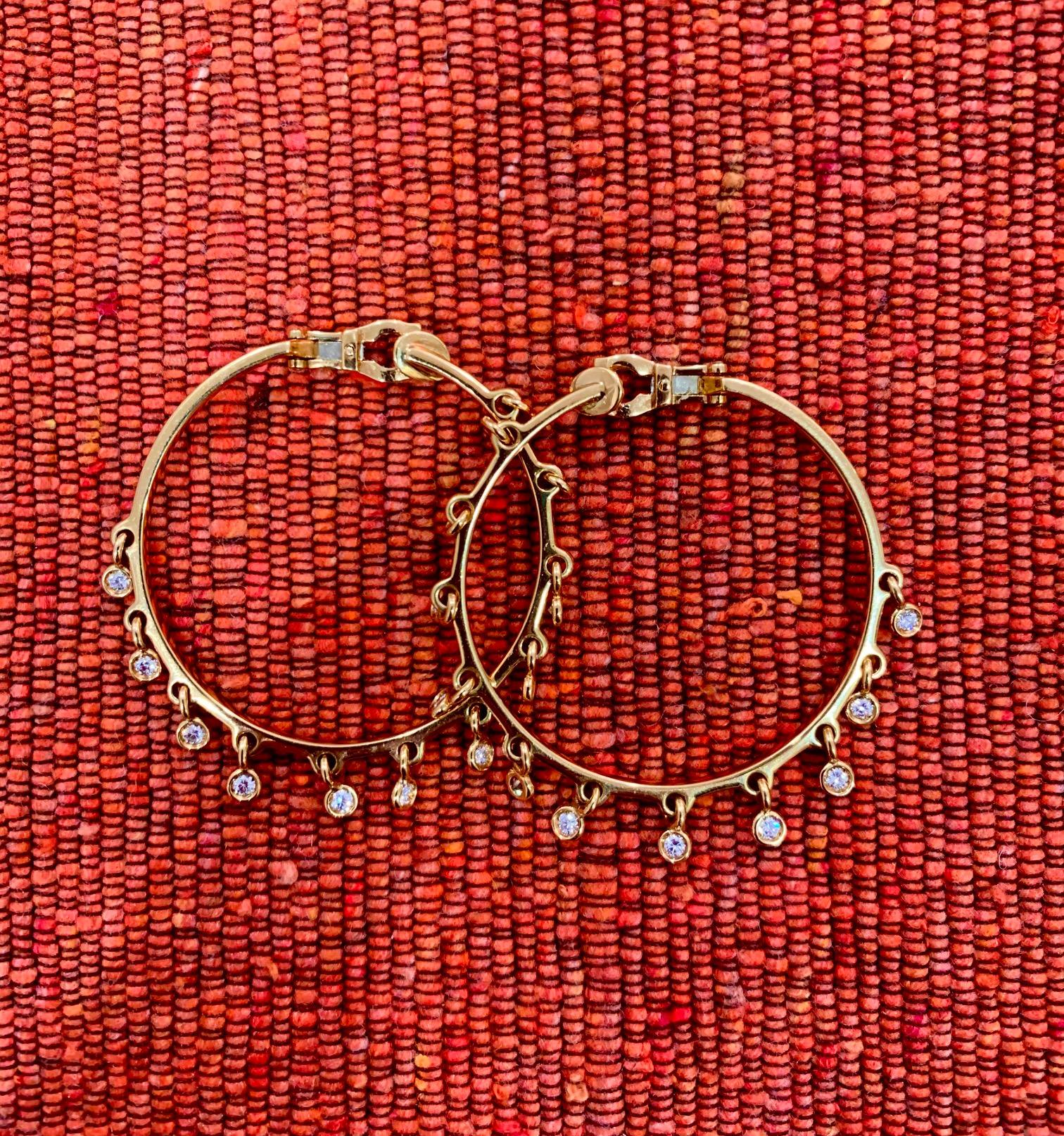 A pair of large diamond and 18 karat yellow gold fringe hoop earrings, with bezel set diamond drops, by Christian Dior. Earrings are signed DIOR 750, numbered, and stamped with French assay marks and maker's marks. 
The diamonds weigh approximately