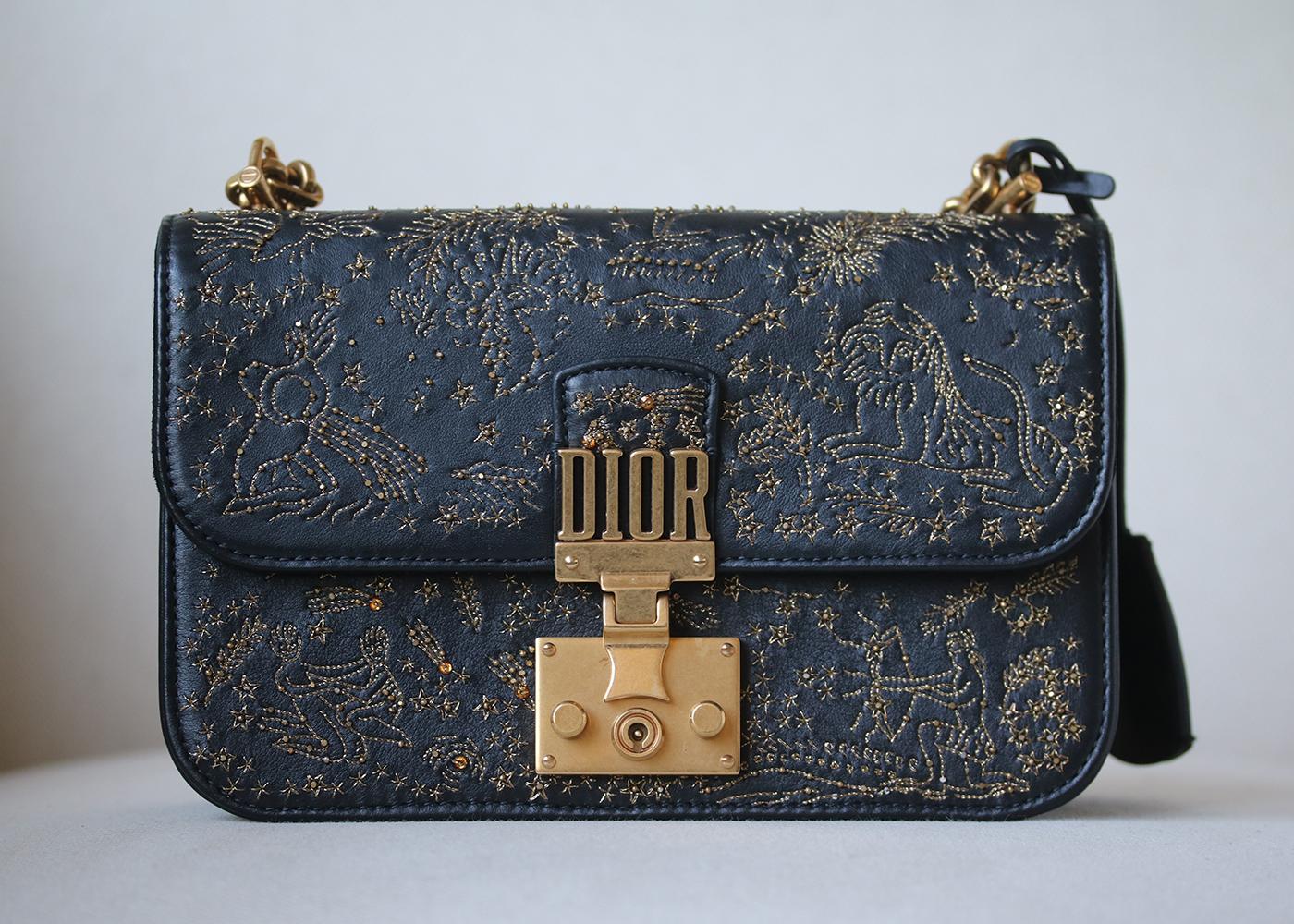 Dioraddict flap bag in black smooth calfskin, embroidered with threads and sequins depicting the signs of the zodiac. Cannage topstitching. Signature clasp. Detachable chain. Jewellery in aged gold-tone metal. Carried on the shoulder or across the