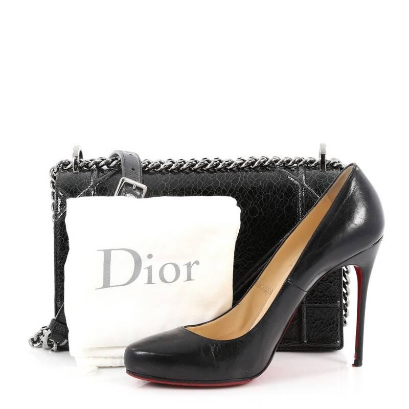 This authentic Christian Dior Diorama Flap Bag Crackled Deerskin Medium displays a modern design with an edgy twist. Crafted in black crackled deerskin leather with a ceramic effect finish, this architectural flap bag features an oversized