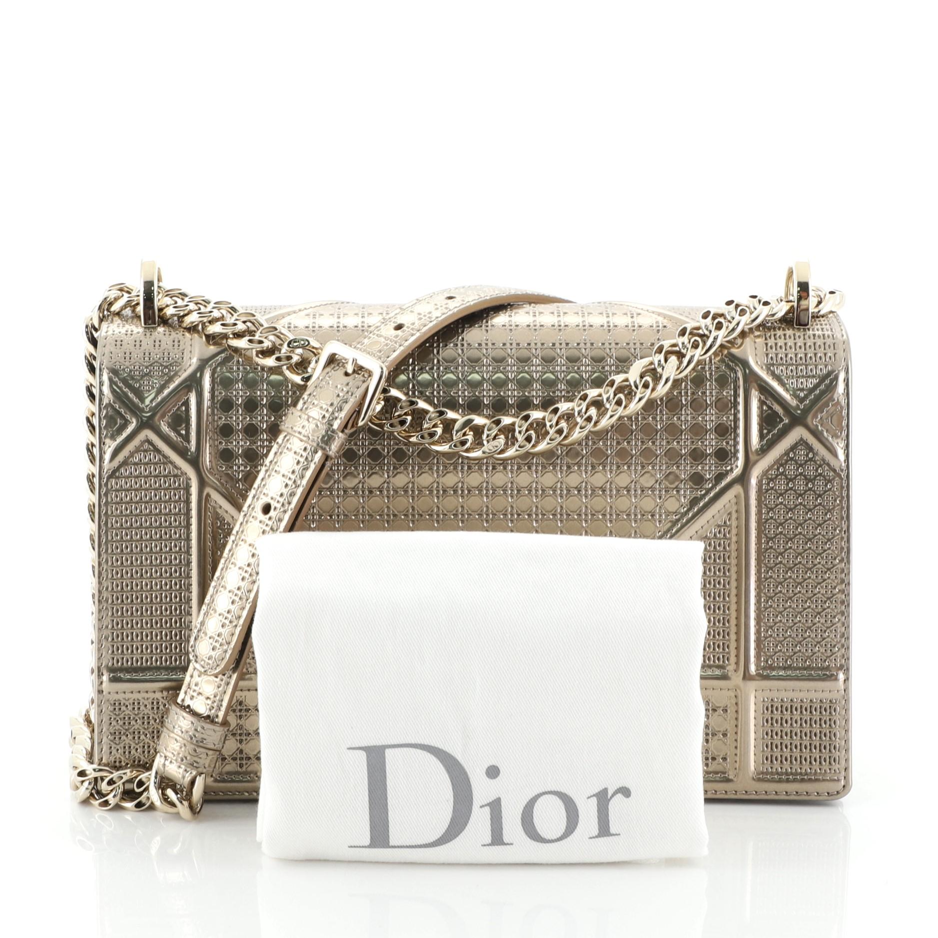 This Christian Dior Diorama Flap Bag Cannage Embossed Calfskin Medium, crafted in gold cannage embossed calfskin, features a graphic-style cannage quilt design, chain strap with leather pad, and gold-tone hardware. Its crest-shaped clasp closure