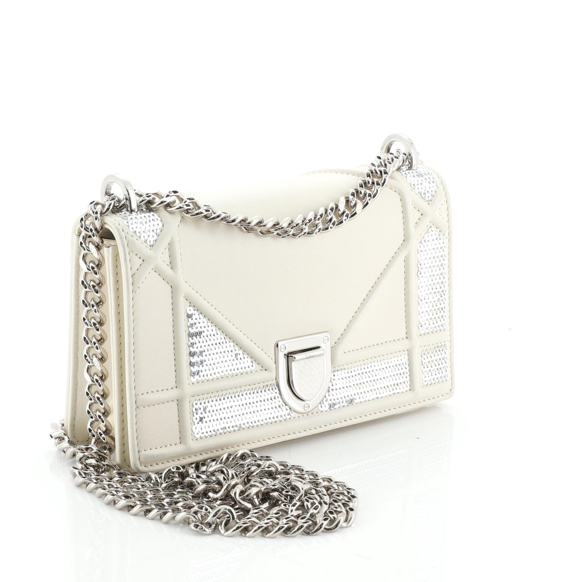 This Christian Dior Diorama Flap Bag Sequin Embellished Lambskin Mini, crafted from white sequin embellished lambskin leather, features embossed and stitched cannage lines, chain link strap, and silver-tone hardware. Its slide-press closure opens to
