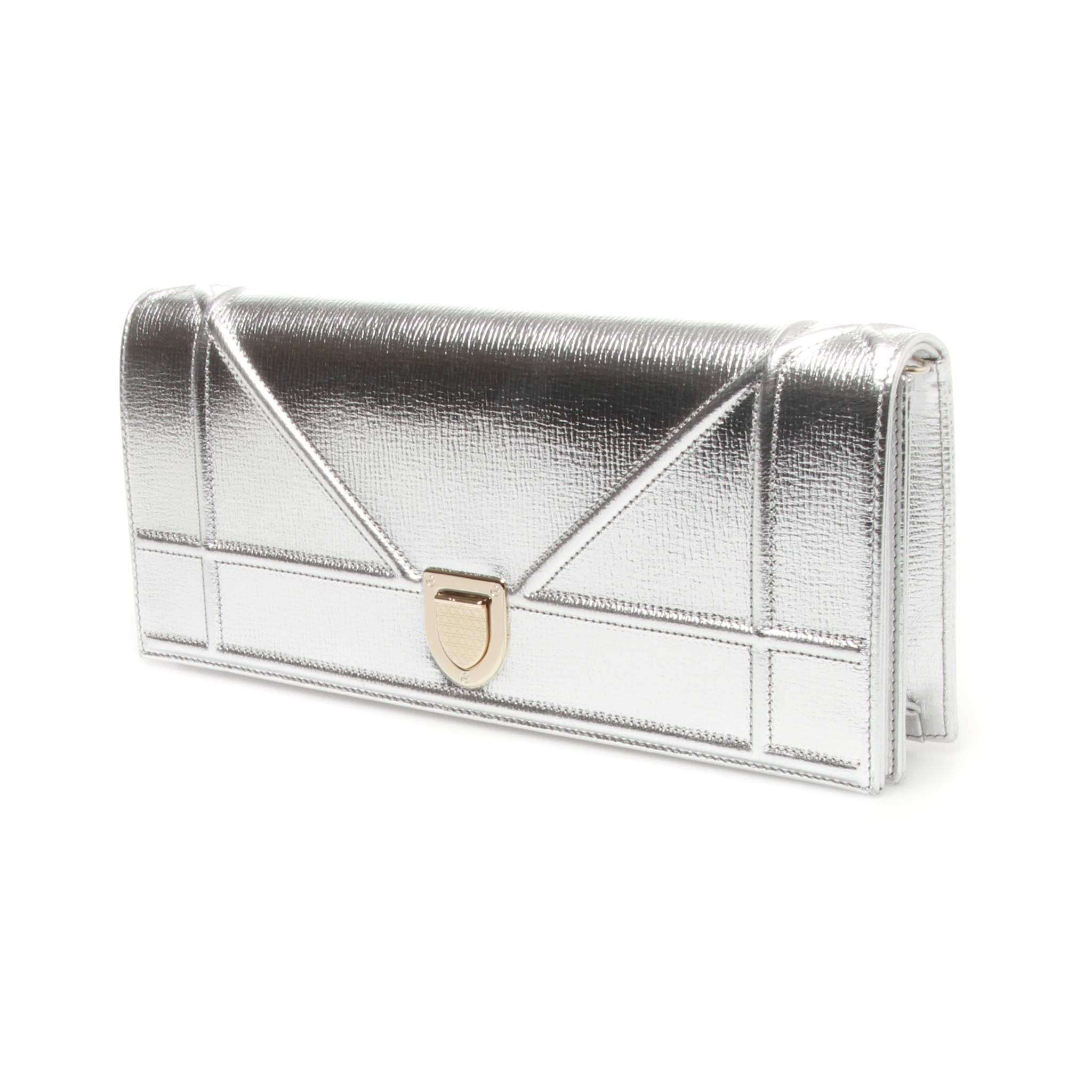 Metallic silver leather Christian Dior Diorama clutch with contrasting gold-tone hardware hardware, pink grosgrain lining, single slit pocket at interior wall and push-lock closure at front flap. Comes with detachable chain to be worn cross body.