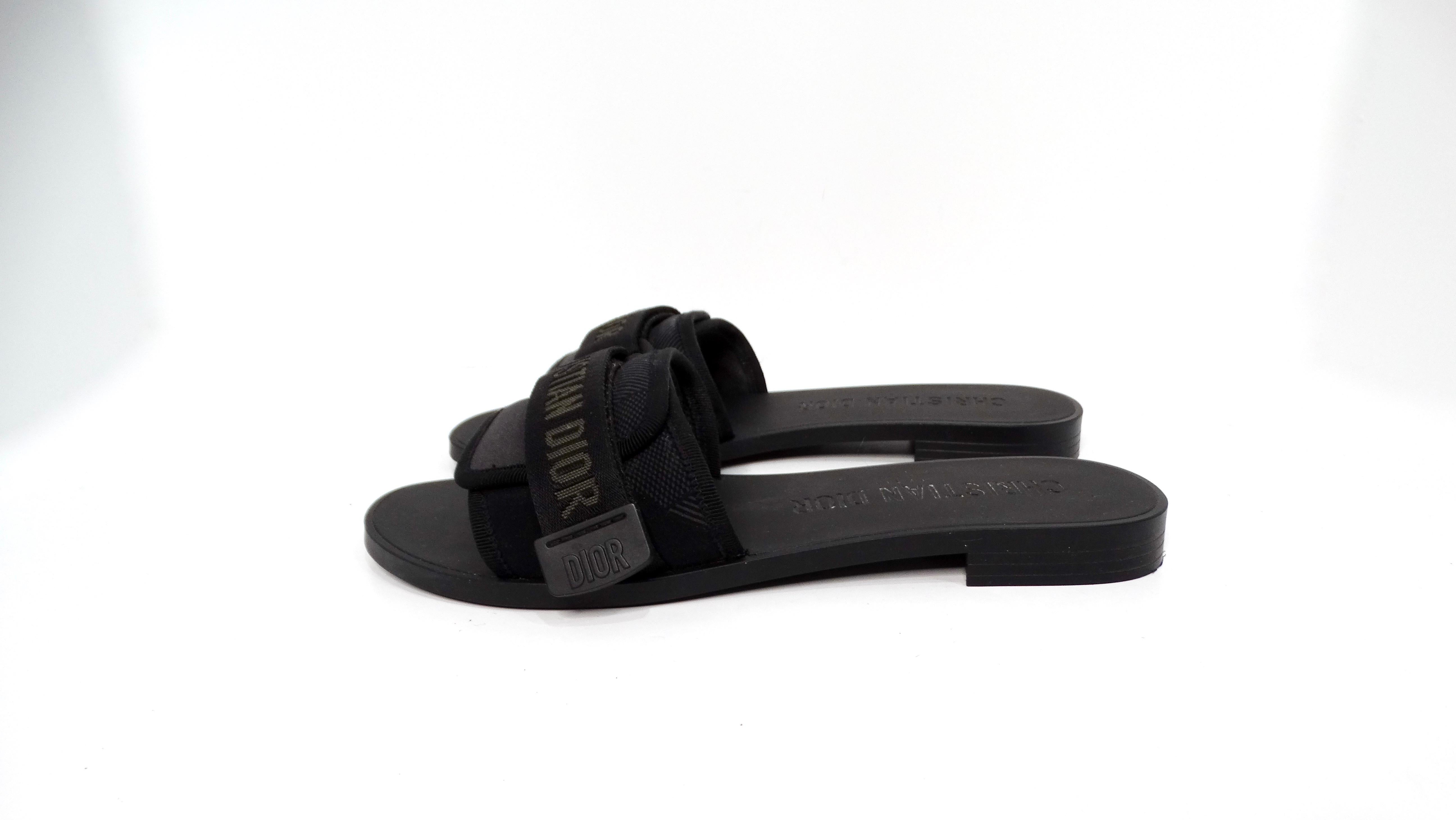 Las Sandalias Christian Dior Dio(r)Evolution Negras con Adornos de Grosgrain y Correa de Velcro ejemplifican una armoniosa mezcla de estilo contemporáneo y lujo. Estas zapatillas vienen en una elegante combinación de colores negro y gris oscuro, que