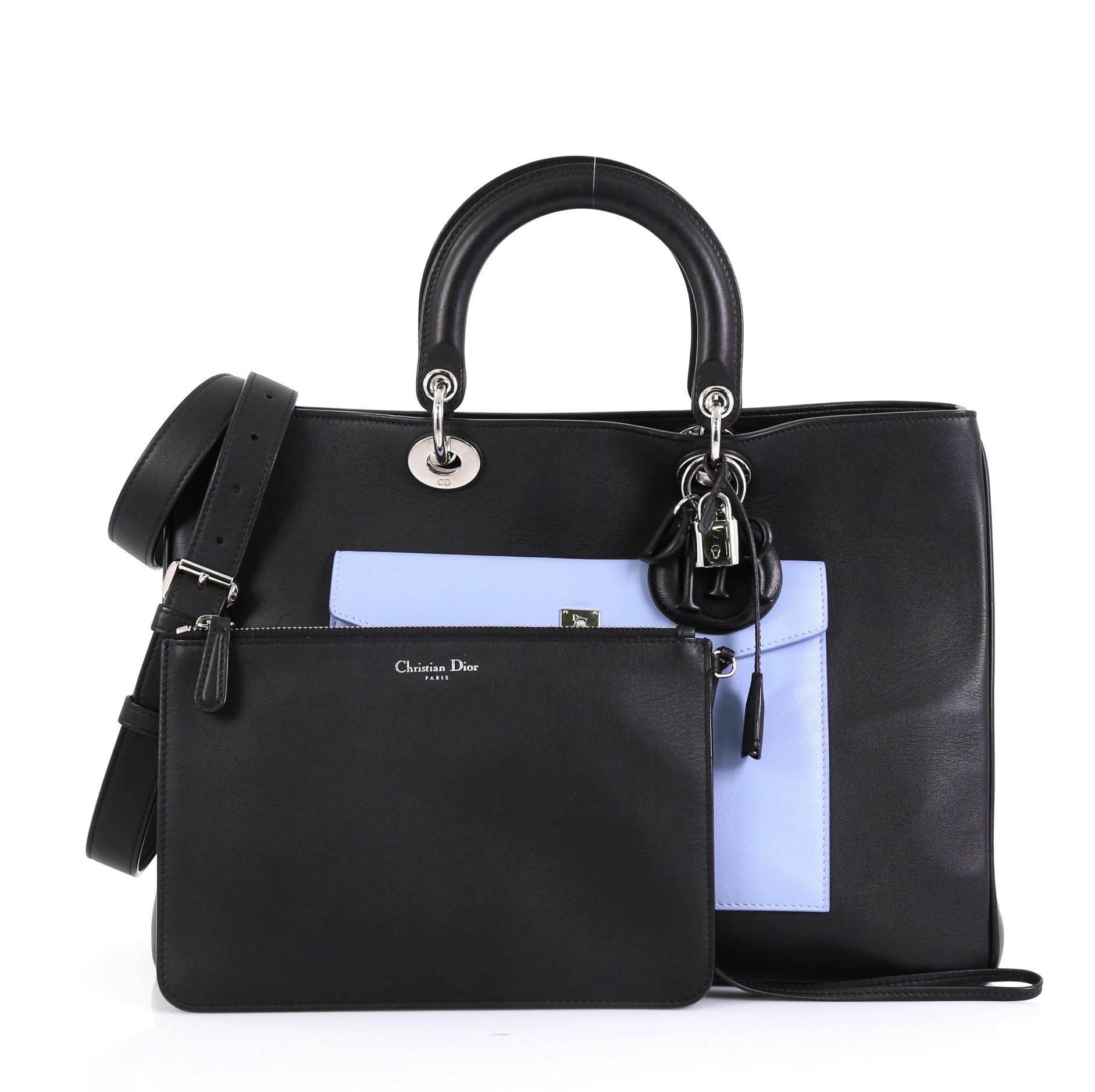This Christian Dior Diorissimo Pocket Tote Leather Large, crafted from black, red and light blue leather, features dual short handles with Dior charms, side snap buttons, exterior front and back flap pockets, protective base studs, and silver-tone