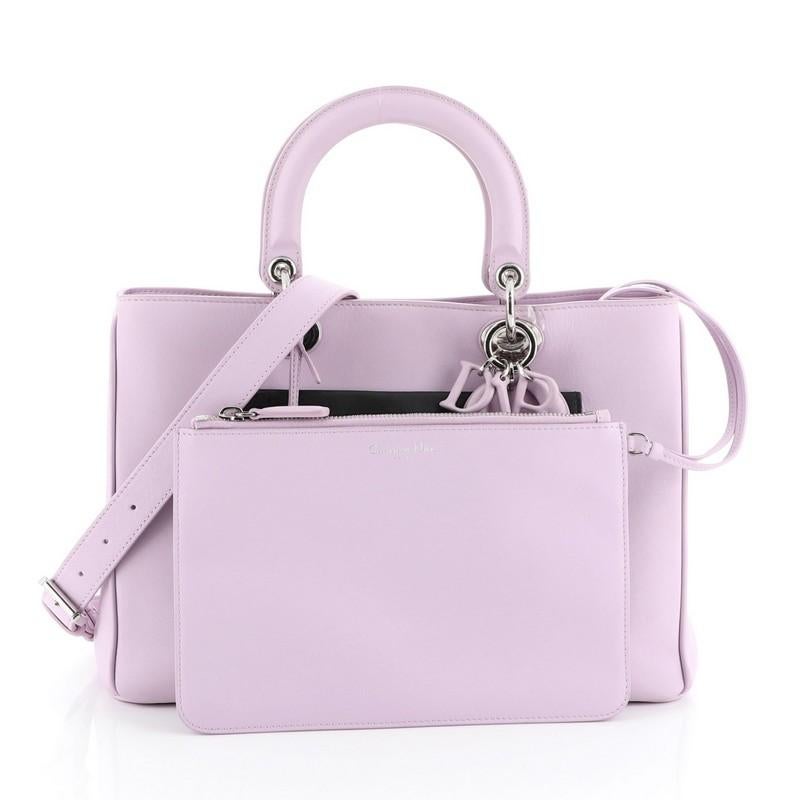 This Christian Dior Diorissimo Pocket Tote Leather Medium, crafted from purple leather, features short dual handles with Dior charms, side snap buttons, exterior front and back flap pockets, protective base studs and silver-tone hardware. Its