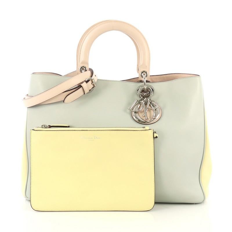 This Christian Dior Diorissimo Tote Smooth Calfskin Large, crafted from multicolor smooth calfskin, features short dual handles with Dior charms, side snap buttons, protective base studs, and silver-tone hardware. Its magnetic snap closure opens to