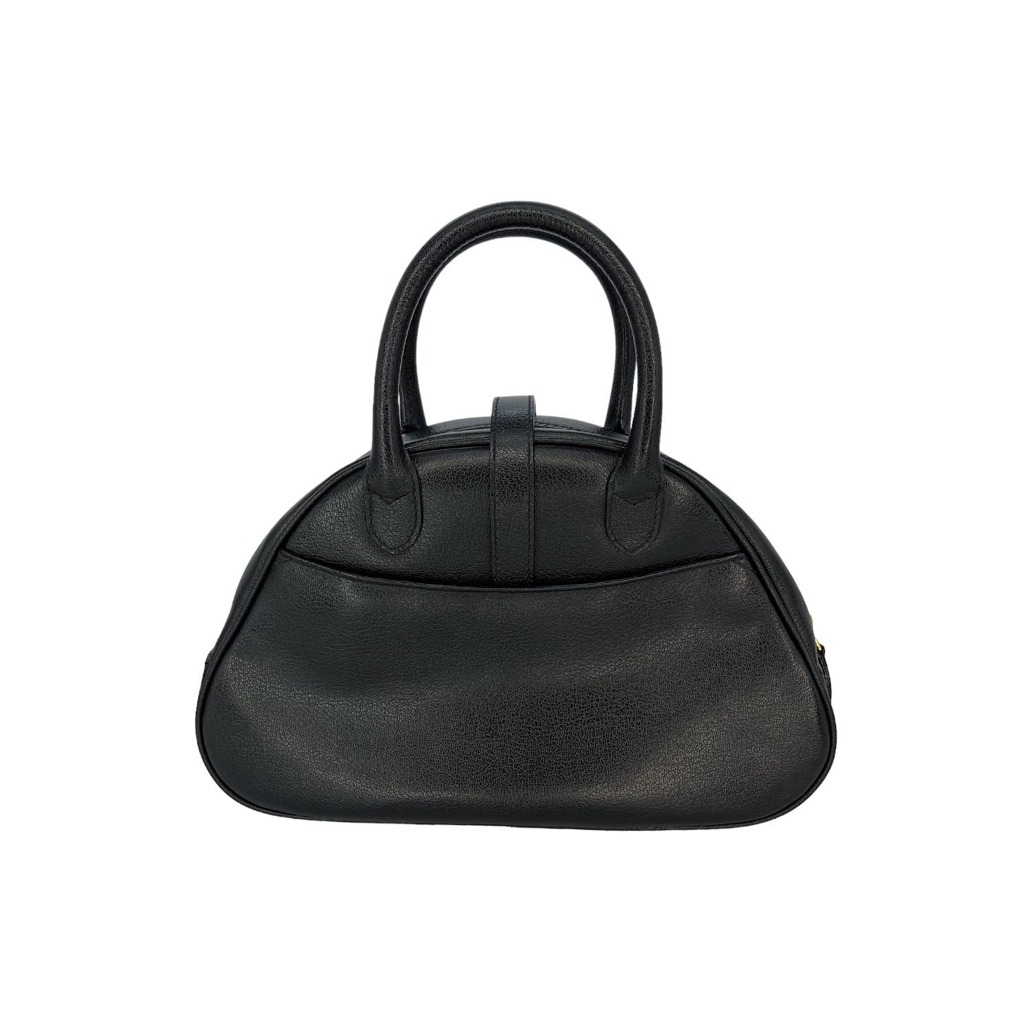 This Christian Dior Double Saddle Bowler Bag was made in Italy and it is finely crafted of a black calfskin leather exterior with gold-tone hardware features such as protective studs at the base and the logo. It has dual rolled leather top handles.