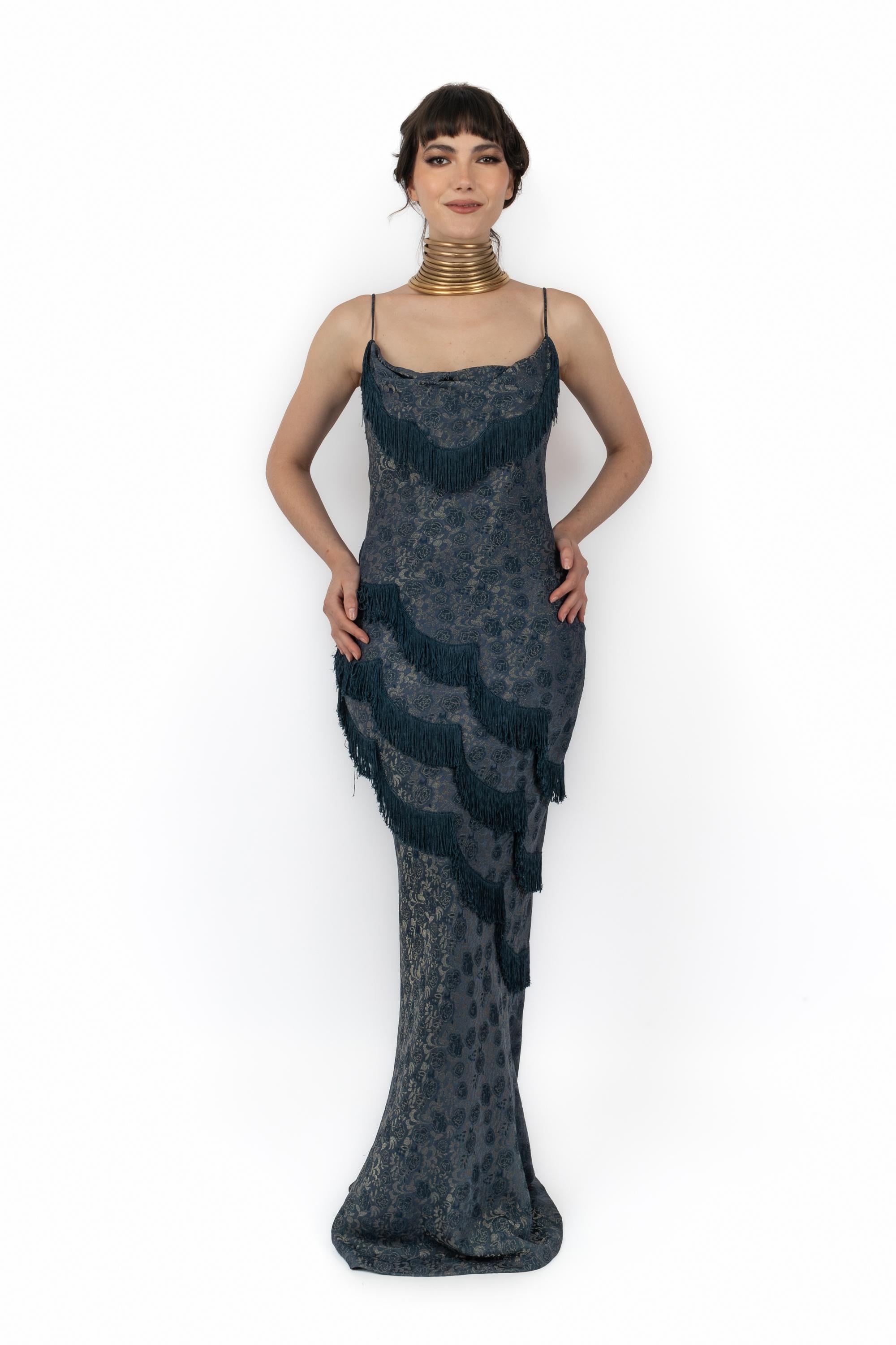 DIOR - Robe en brocart bleu à bretelles, coupée en biais, décorée de roses dorées et ornée de franges. Aucune taille n'est indiquée, il s'agit d'un 36FR. Collection 1998 printemps-été sous la direction artistique de John Galliano.

Condit :
Très bon