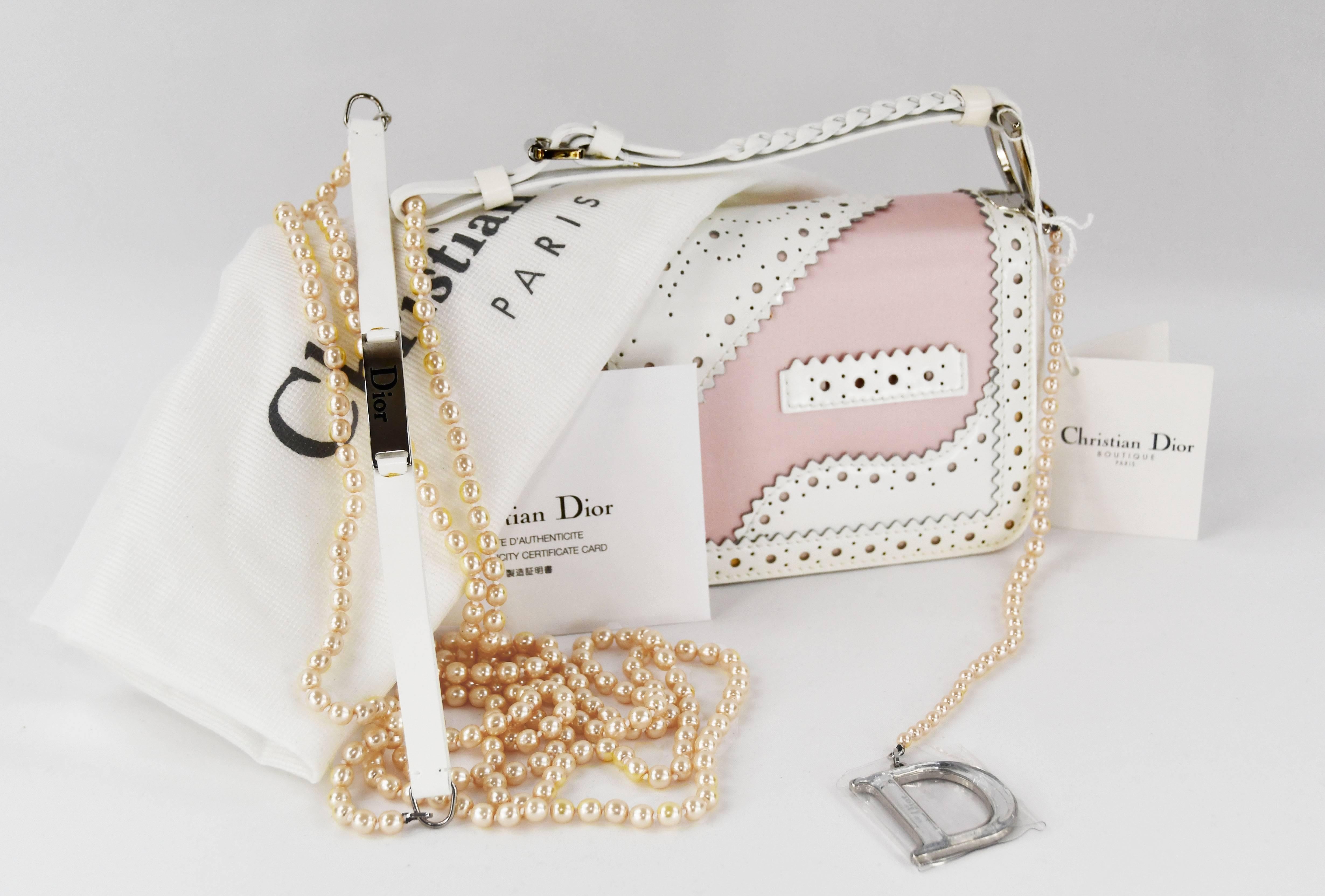 This is an exquisite Christian Dior patent D'Trick shoulder bag.  It is made out of pink and white leather that resembles the style of patent leather shoes with clutch handle with pearl necklace attached.  New with tags.  Bag measurements 8.5 inches