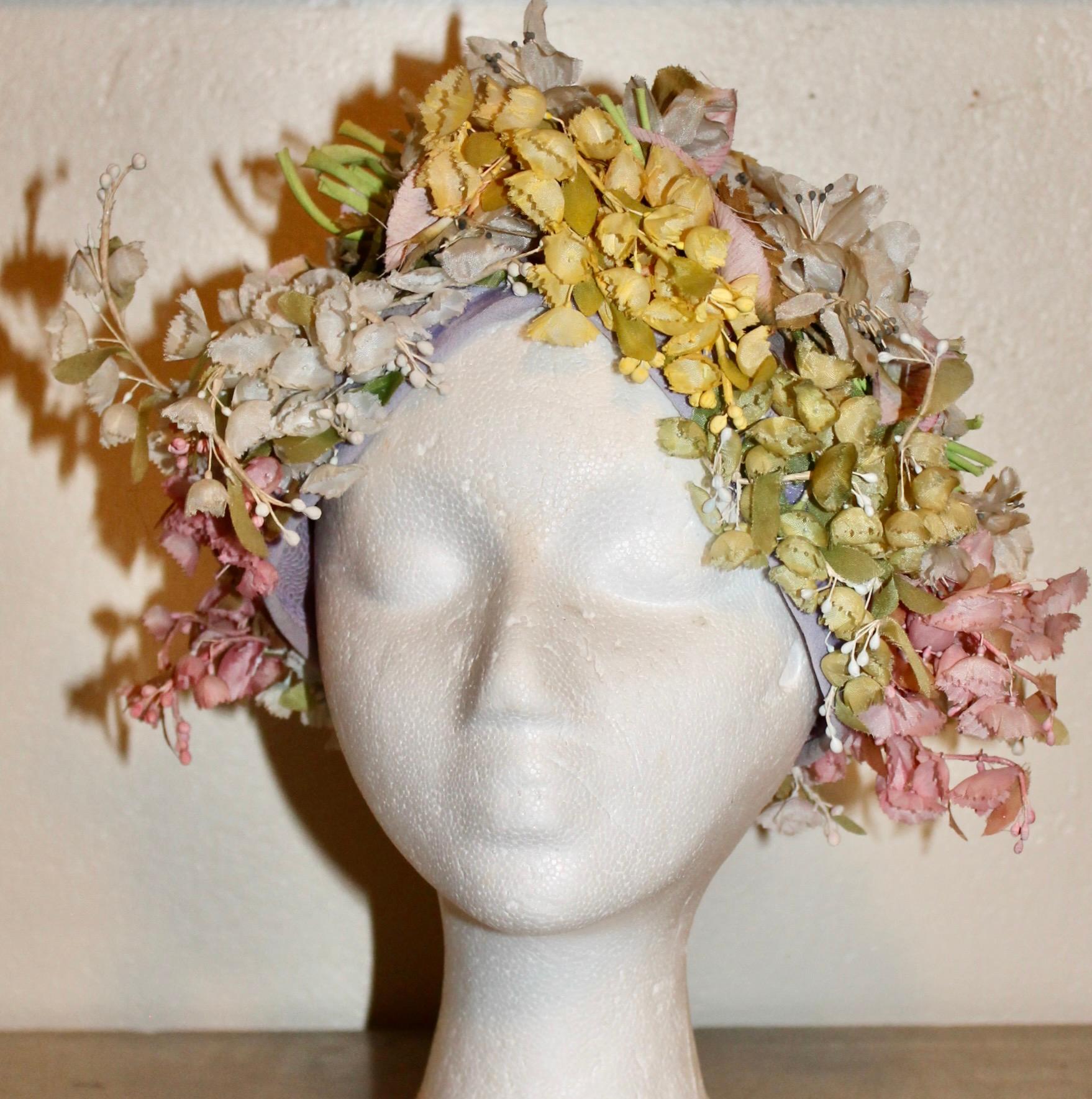 Trimmed with yellow and white lily of the valley organza silk flowers and leaves attached to a pinkish/white fine woven mesh fabric support.  Circumference 22
