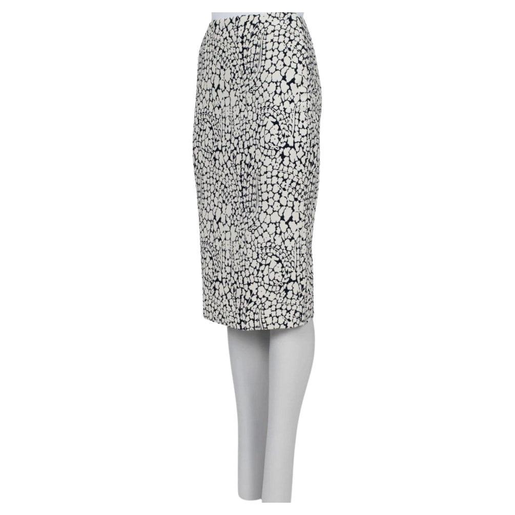 Cette élégante jupe crayon Christian Dior présente un superbe imprimé floral monochrome, parfait pour ajouter une touche de sophistication à votre garde-robe. La silhouette ajustée assure une coupe flatteuse, tandis que la fermeture à glissière au