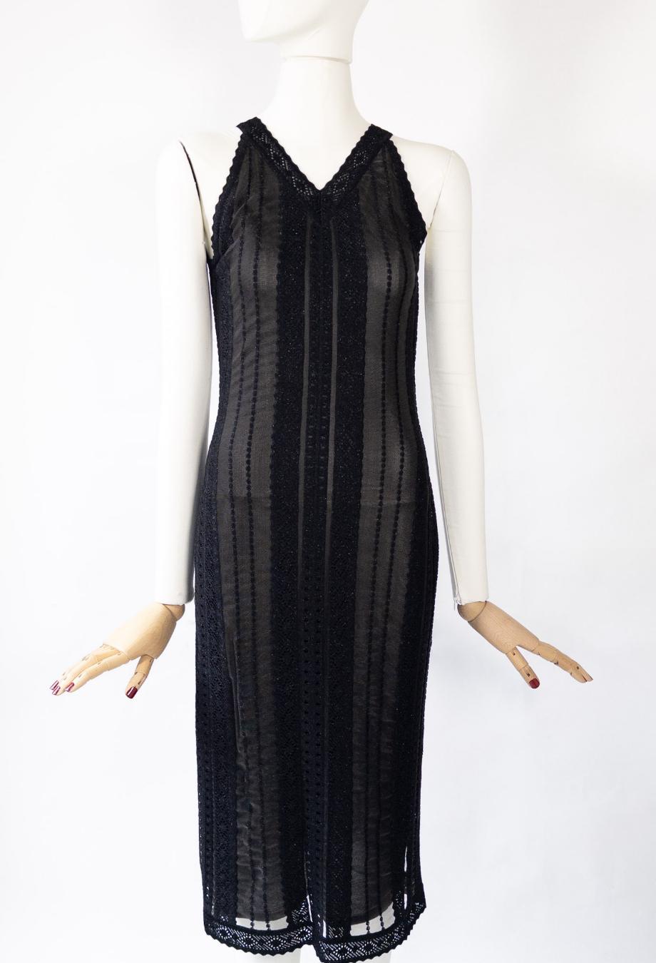 This rare Christian Dior midi dress hails from John Galliano’s celebrated era. Cut from sheer black mesh and trimmed with glittering vertical lace panels, the silhouette skims the body with a refined, lingerie-inspired allure that’s unmistakably