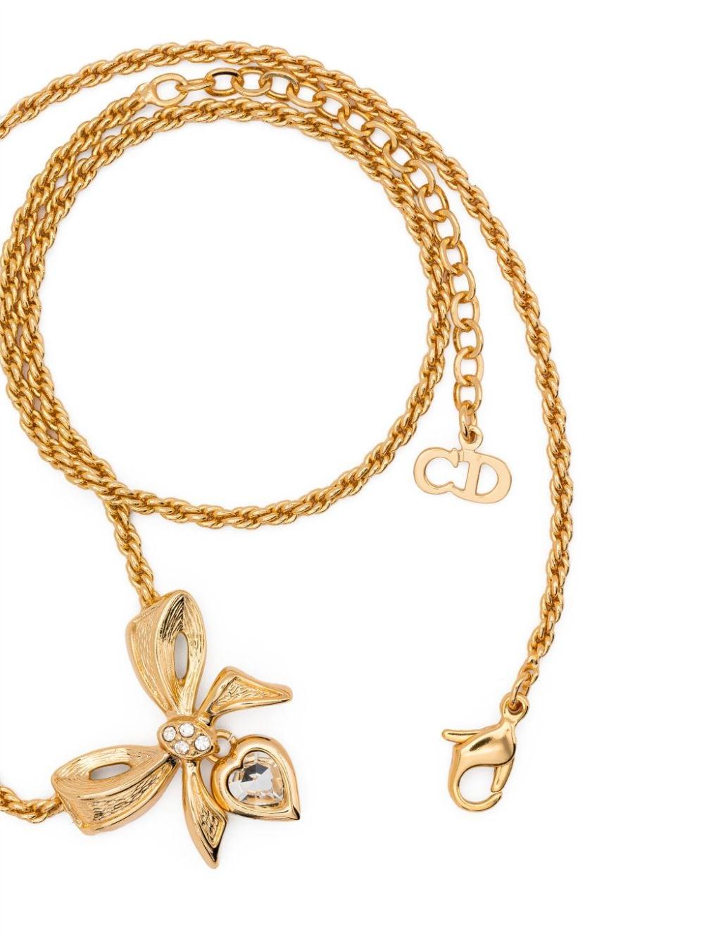 Dior gold-tone rhinestone-detailing bow-pendant necklace featuring bow pendant, heart charm, rhinestone detailing, signature CD logo charm, adjustable fit, rope chain, lobster claw fastening.
Length 17.3 in (44 cm)
Pendant Length 0.9in (