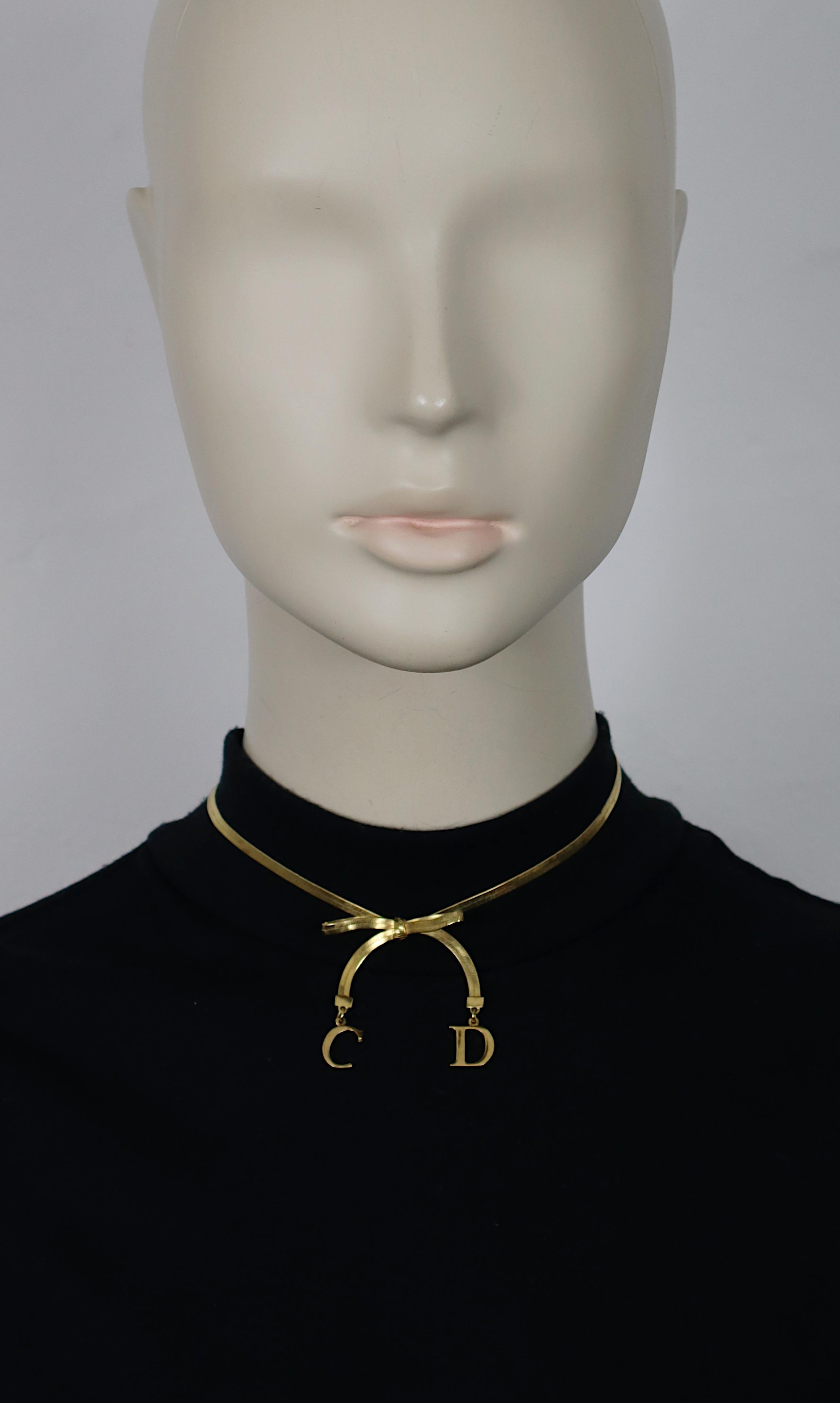 CHRISTIAN DIOR gold tone flat herringbone necklace featuring a bow and C D initial charms.

Adjustable hook clasp closure.

Embossed DIOR.

Indicative measurements : adjustable length from approx. 32 cm (12.60 inches) to approx 36 cm (14.17